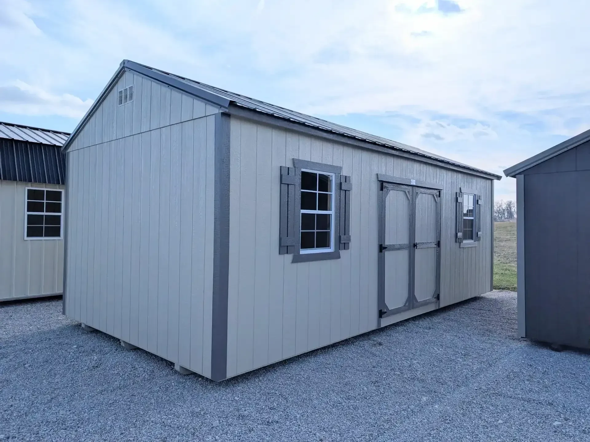 a large garden shed with 72" double doors and a 2x3 window with shutters on each side of them.