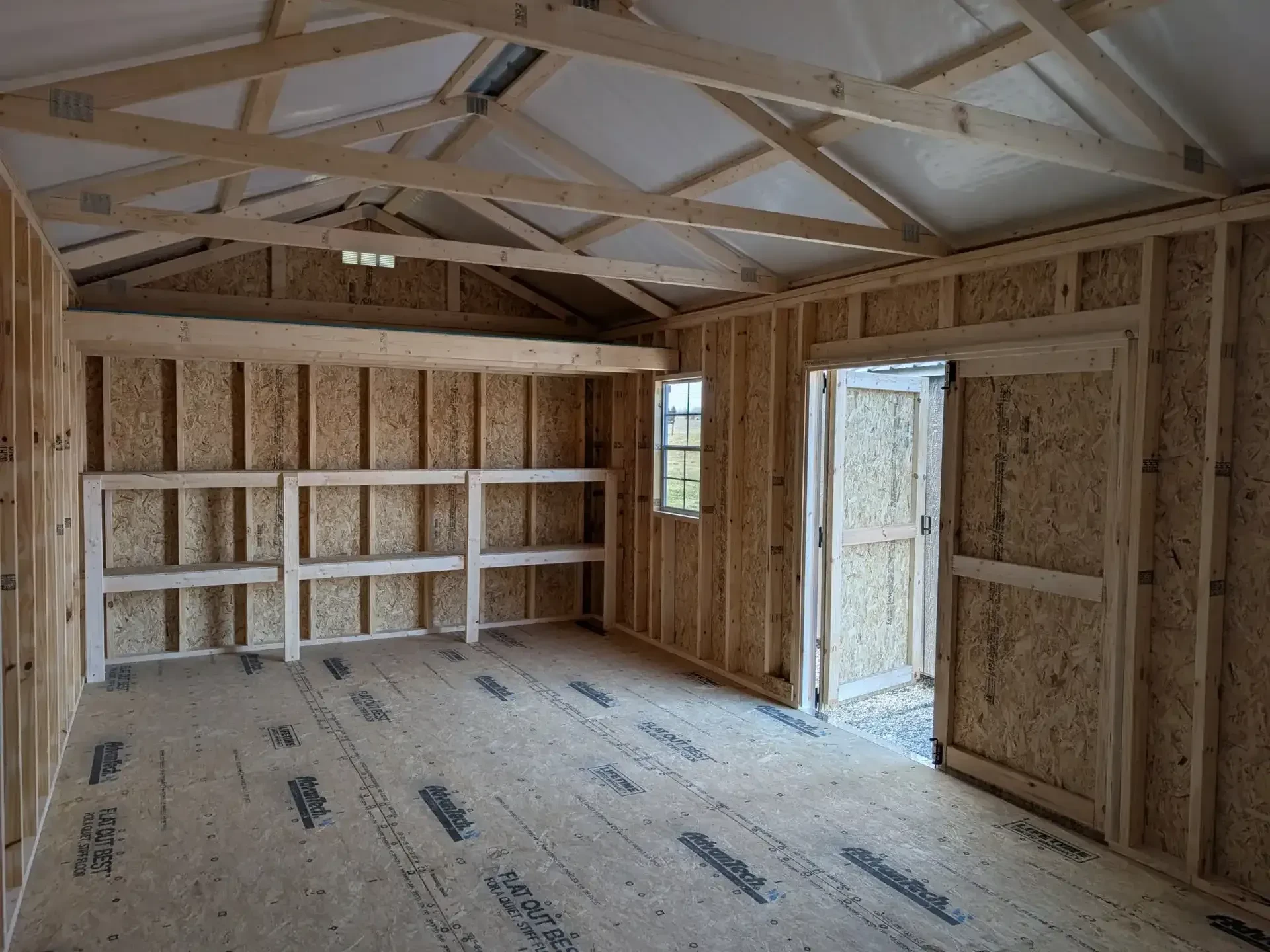 inside a wood garden shed looking at the right wall. It has double shelves and a loft along the wall