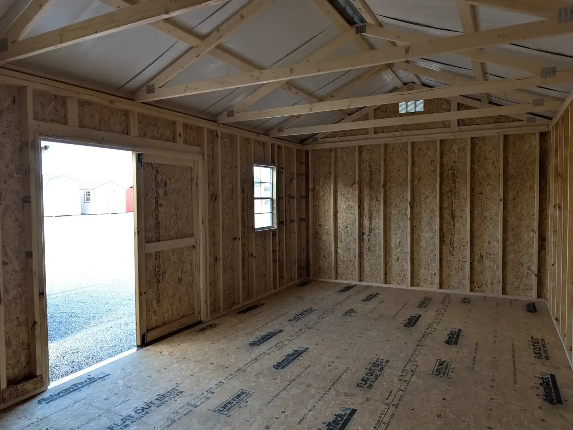 inside a wood garden shed looking at the left wall, it has nothing but you can see the window on the front wall