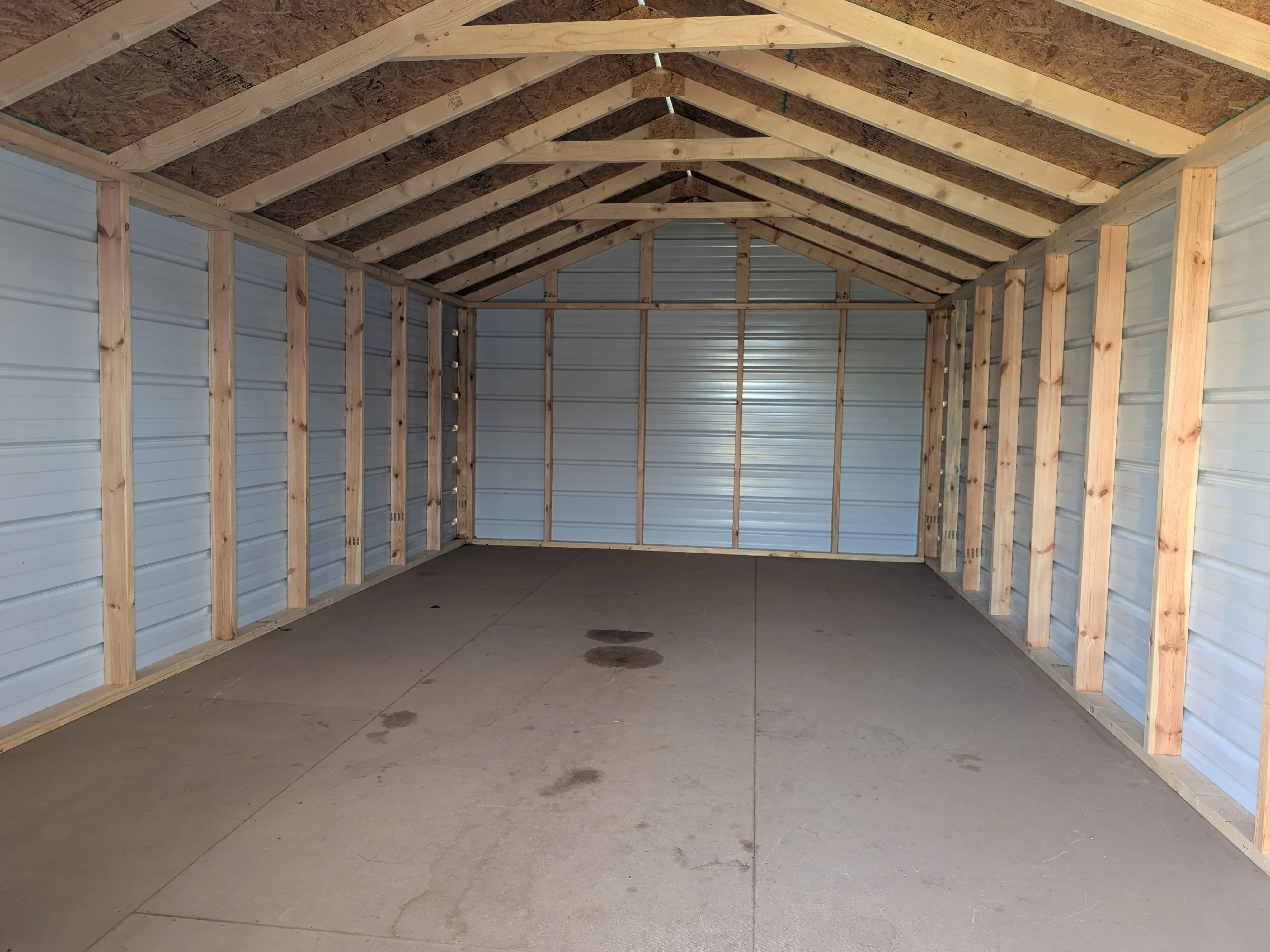 the inside of a metal utility shed. It has a solid floor and you can see the lumber framing