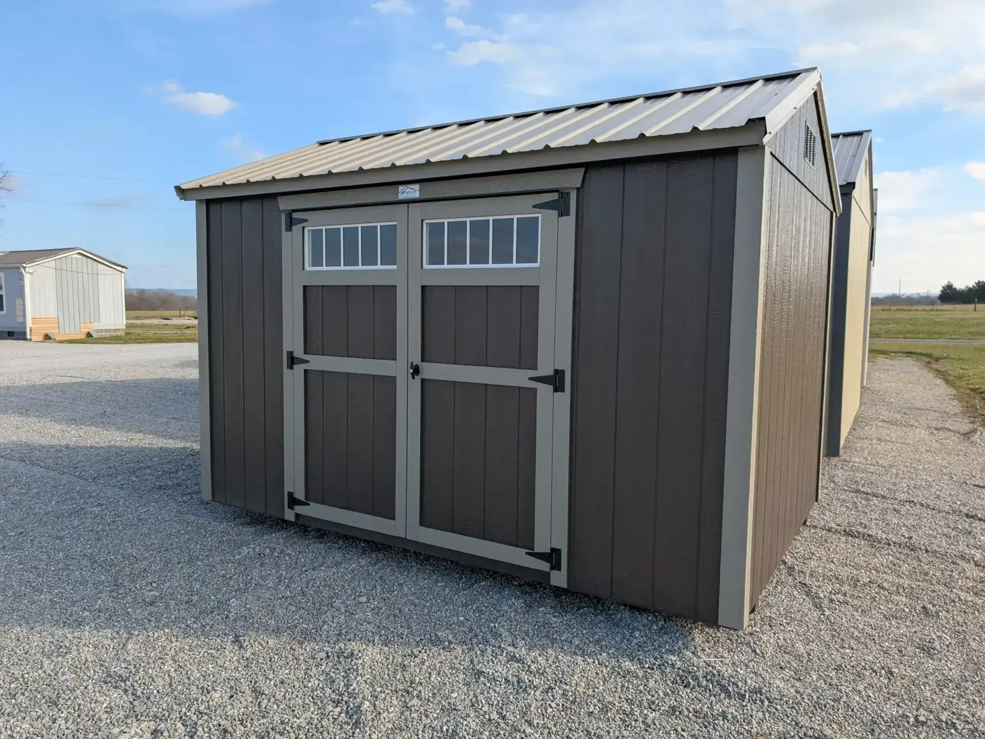 a bronze colored garden shed with double doors, the double doors have transom windows in them.