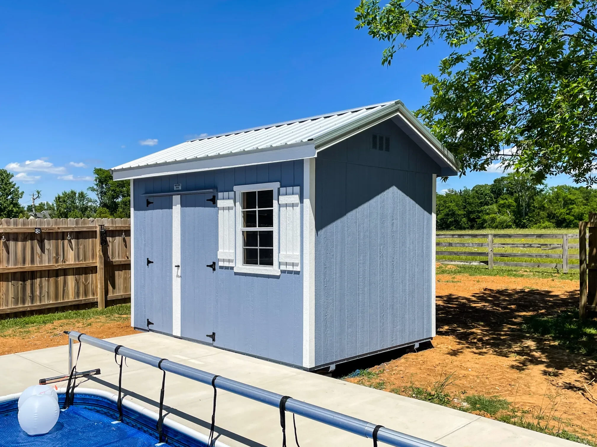 a light blue small shed beside a pool