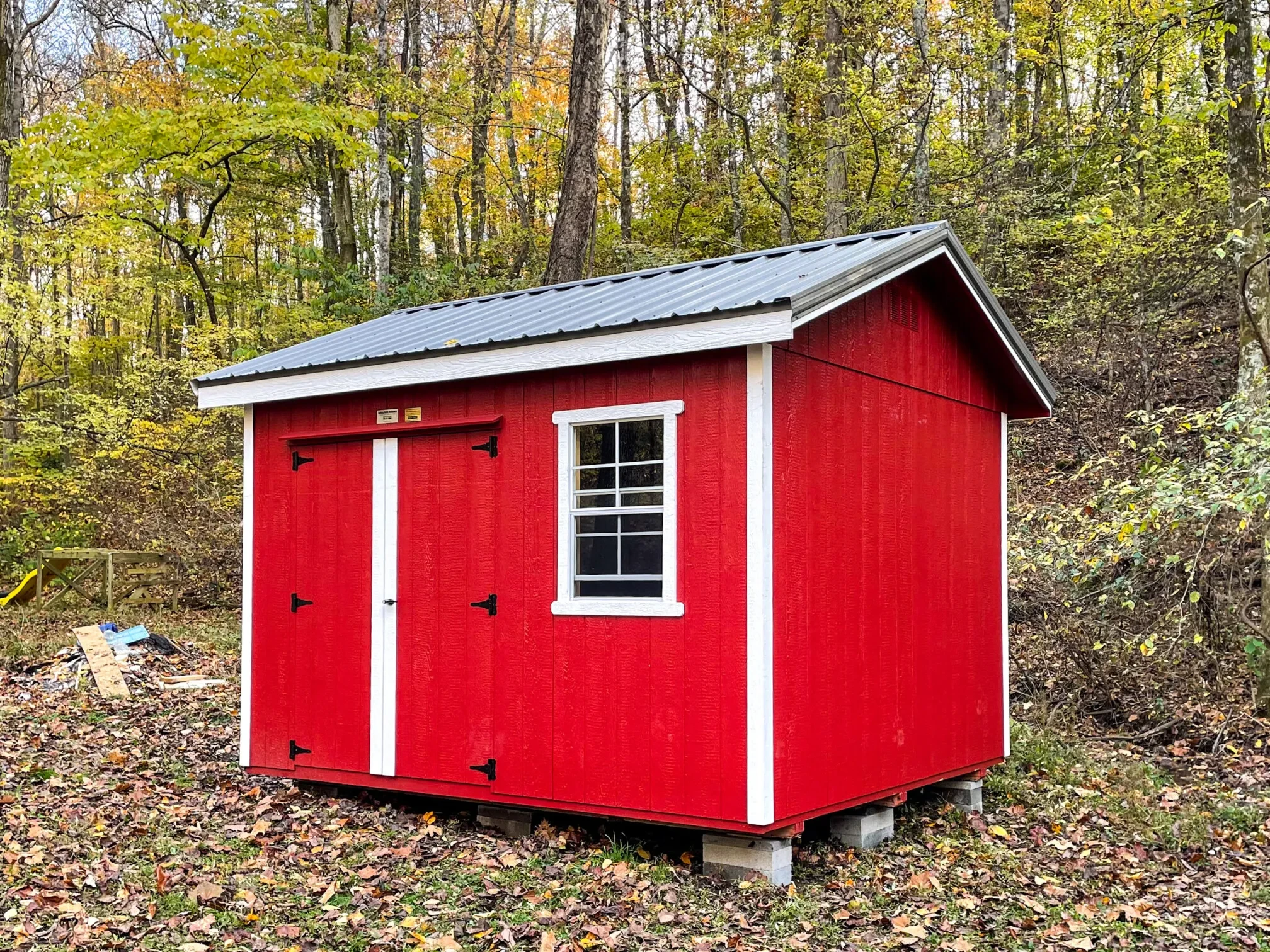 A small bright red shed sitting in the woods