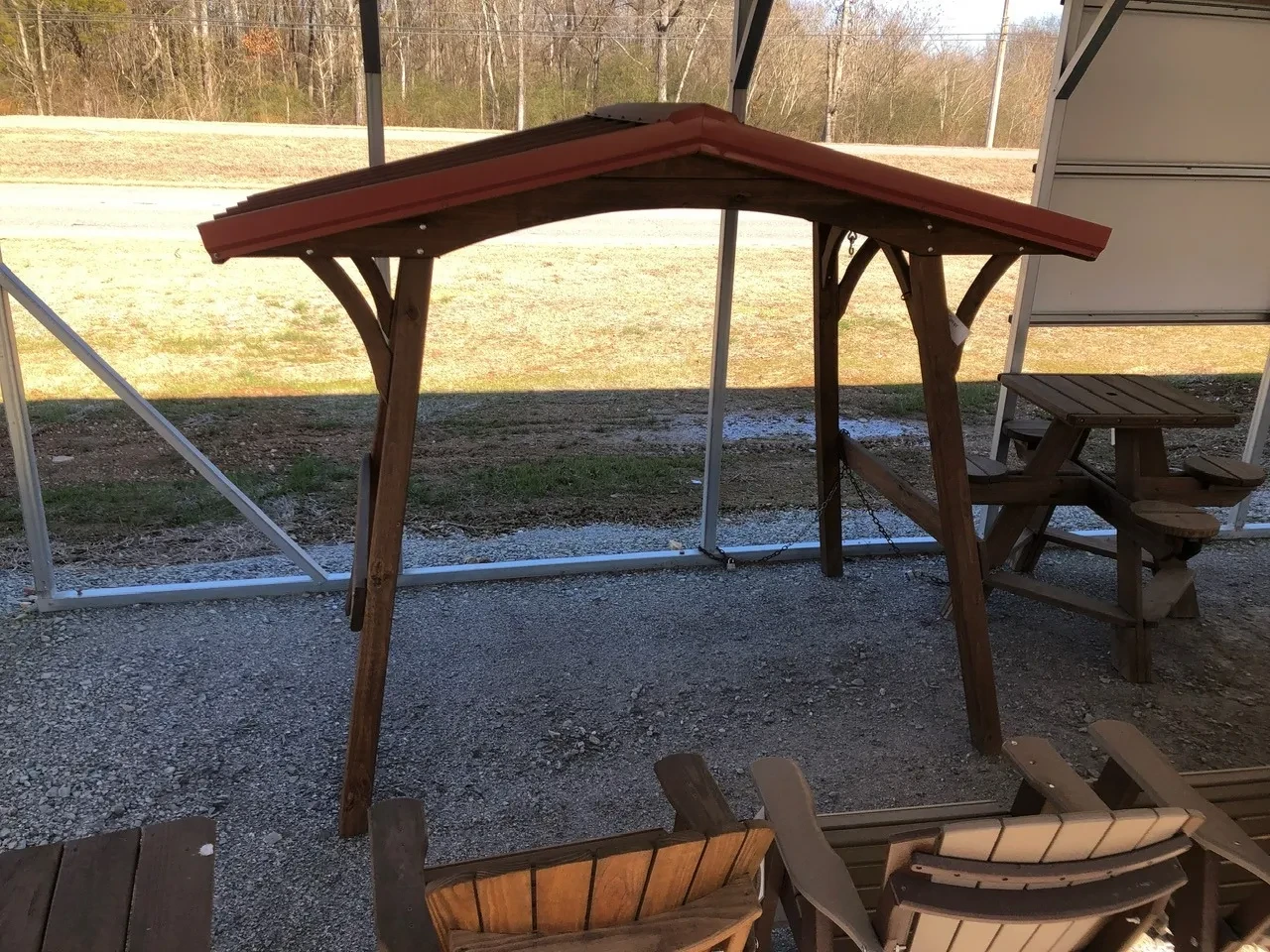 a wood swing cover with a red metal roof