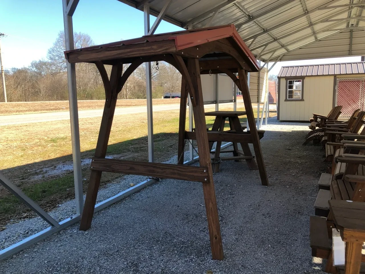 the side view of a wood swing cover with wood bracing and a red metal roof
