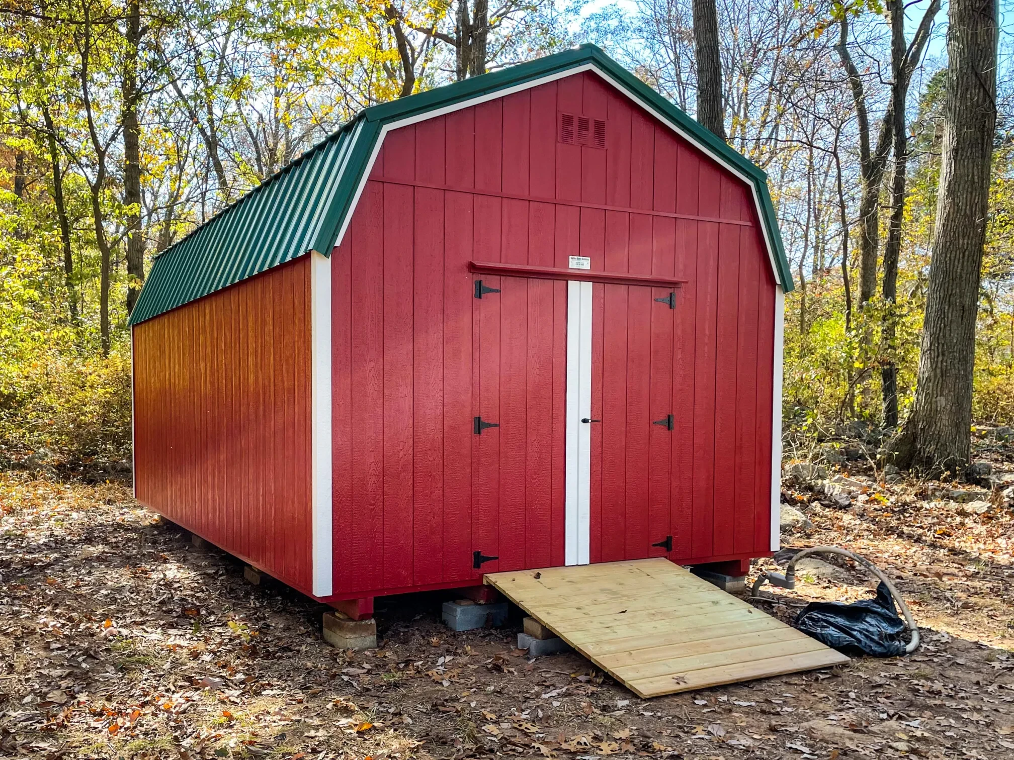 A bright red lofted barn with a green metal roof and white trim