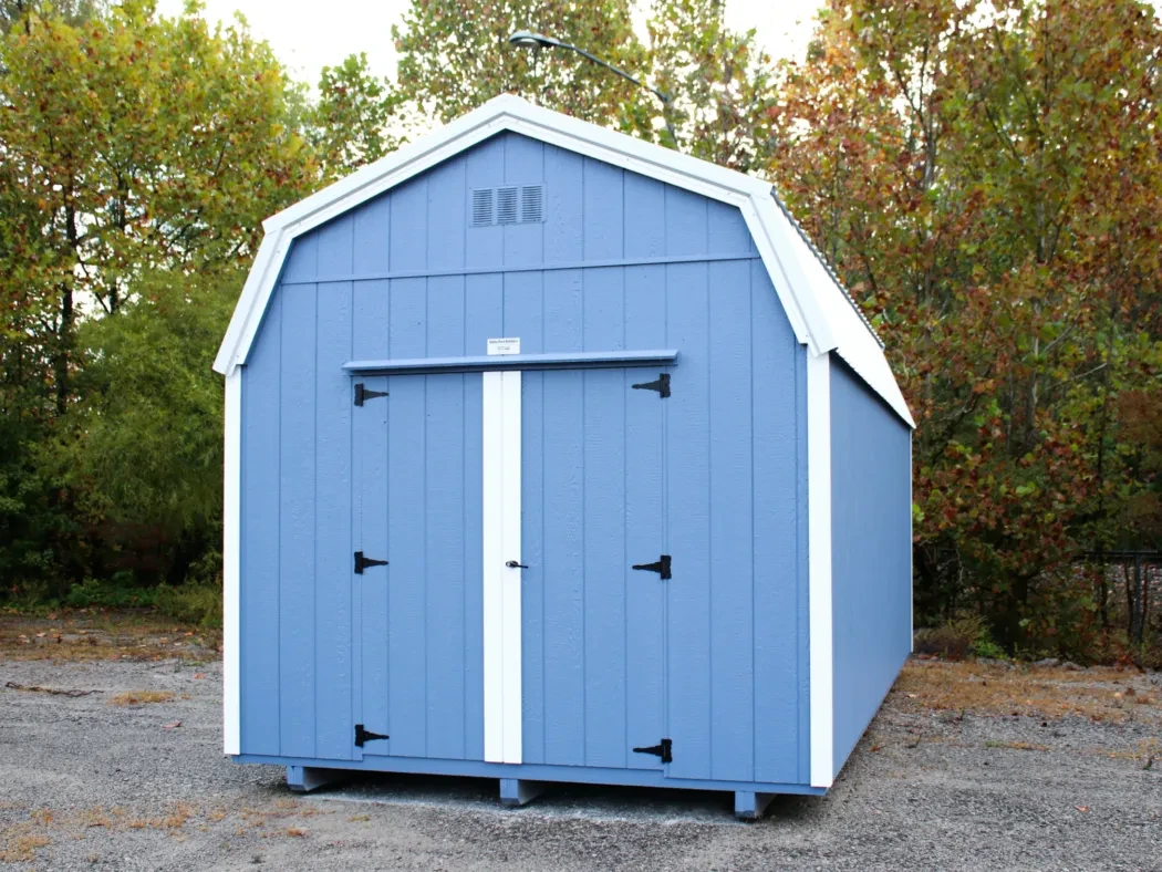 a light blue lofted shed with a white roof and trim