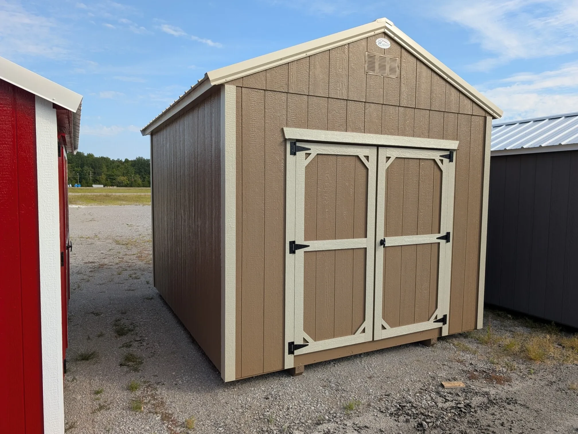 A corner view of a 10x12 wood shed that is pine bark colored with light stone colored trim.