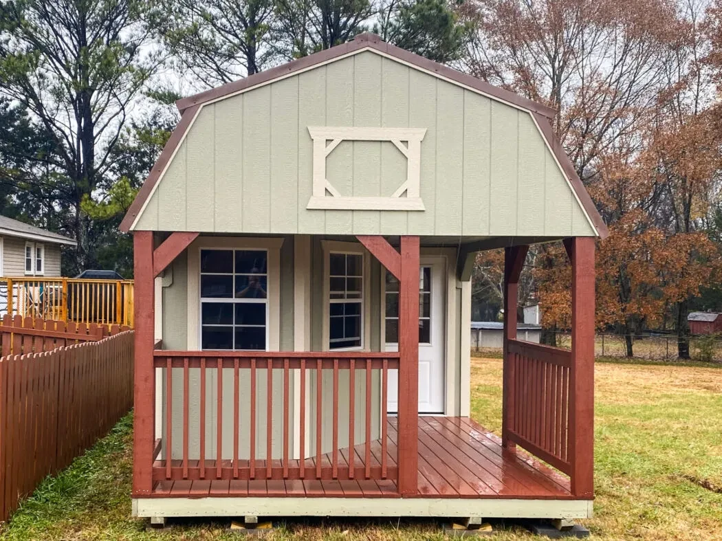 a wood shed with a reddish stained wood L-shaped porch