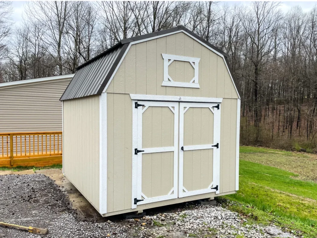 a stone colored lofted barn with white trim and a black roof