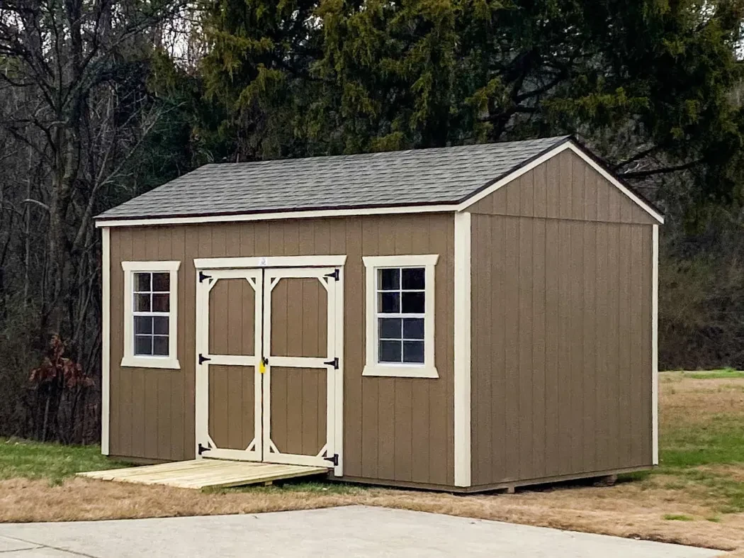 A brown and tan wood shed with a shingle roof