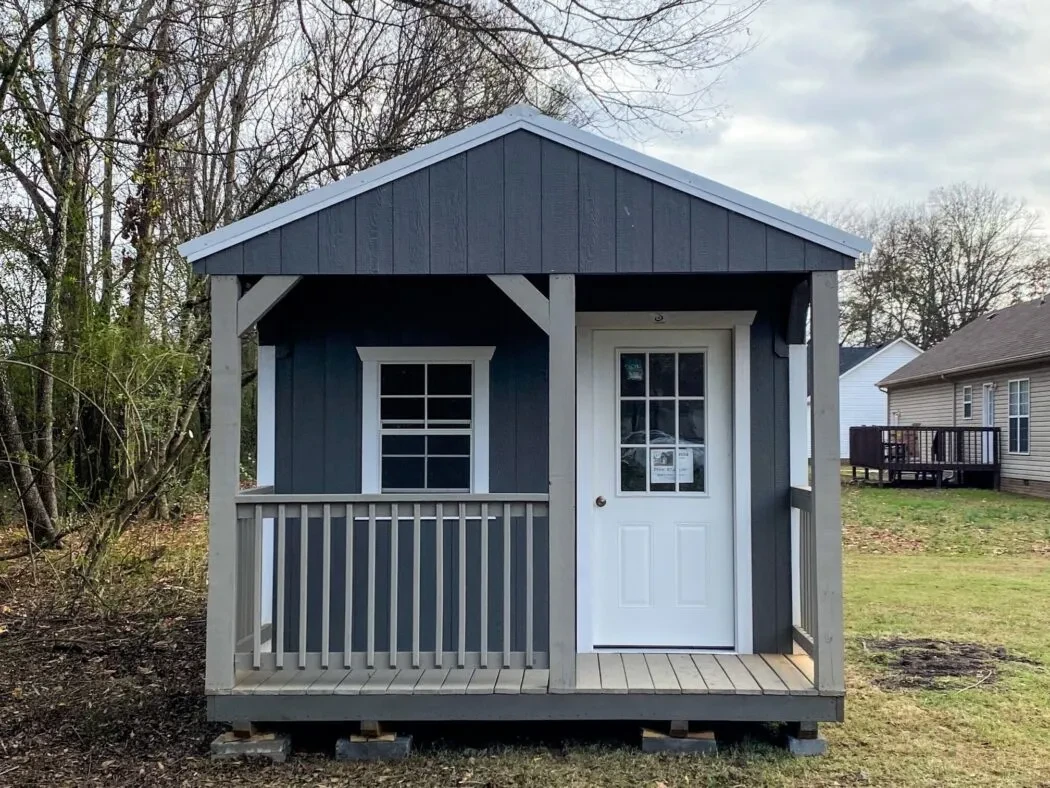 A dark blue cabin with a porch on the front