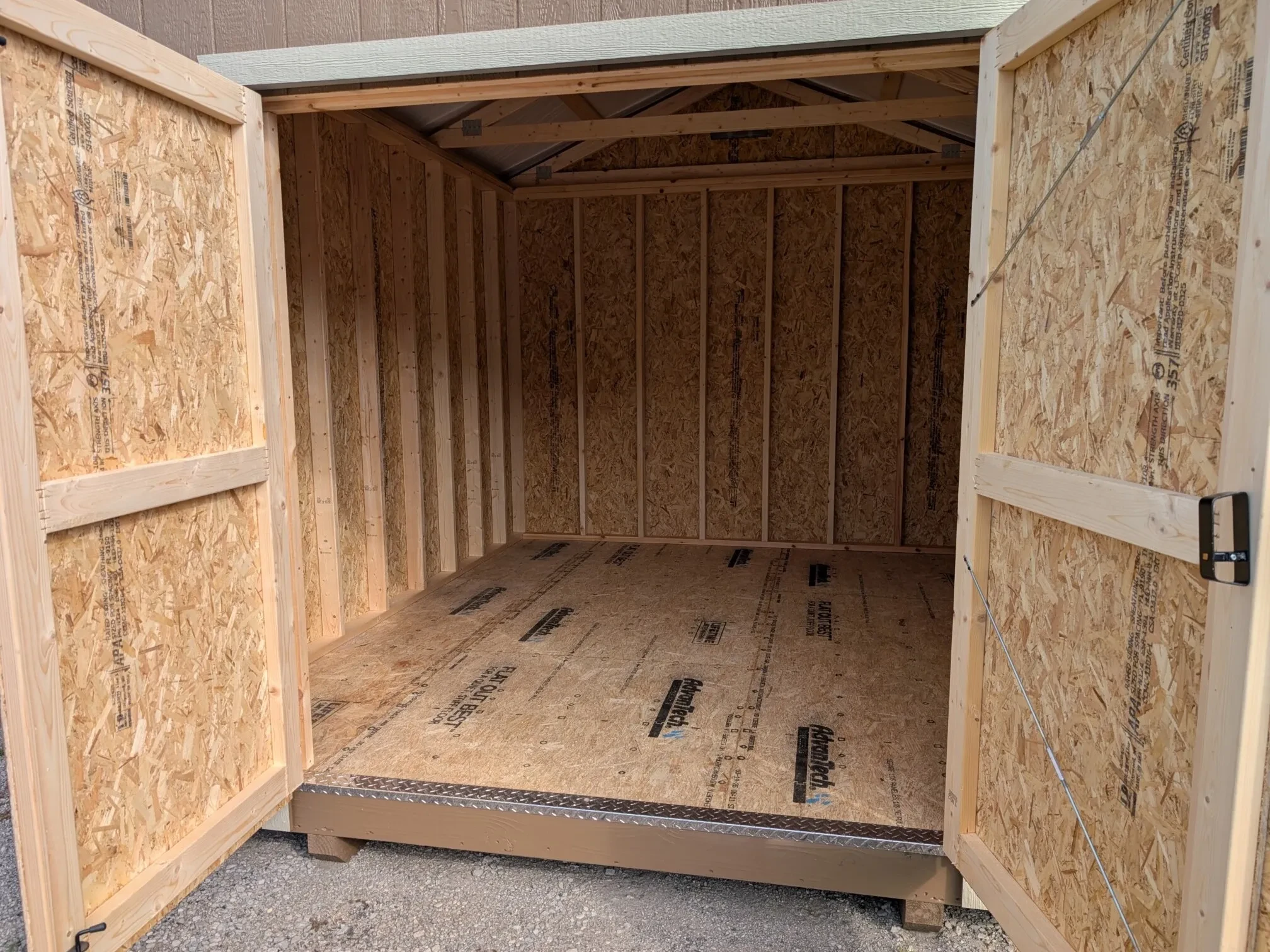 The inside view of a wood shed through the double doors which are open.