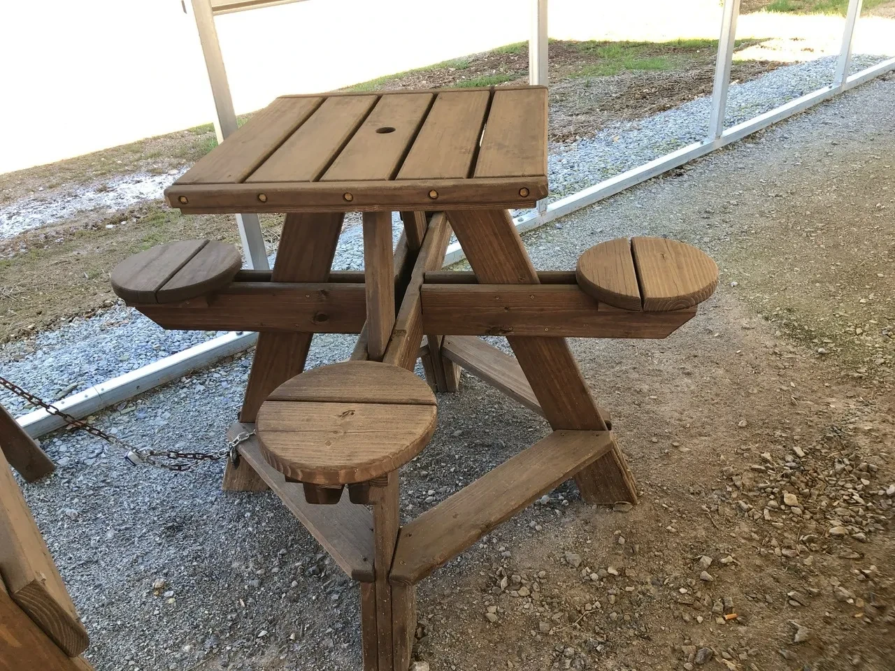 a wood stained table with circular seats. The tabletop is five horizontal planks of wood