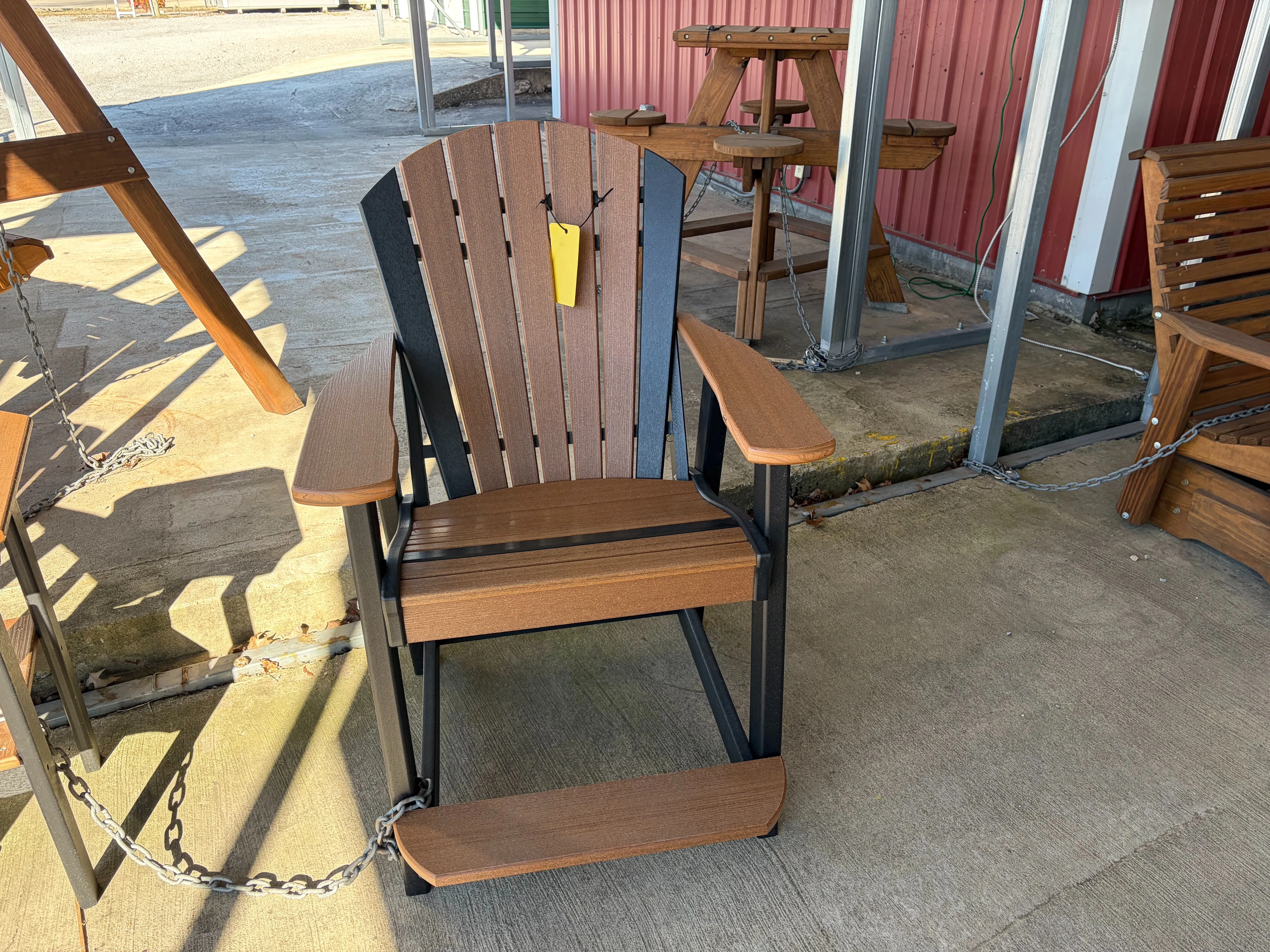 a chair made out of polywood that is mostly brown and has black accents colors, it is chained to a polywood end table
