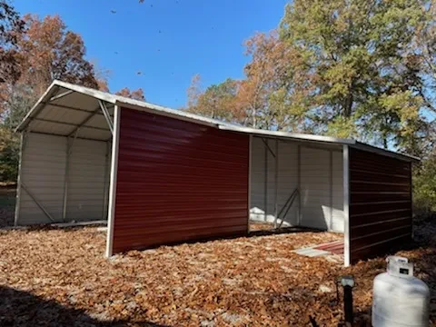 A red mostly enclosed carport with a partial lean-to on one side