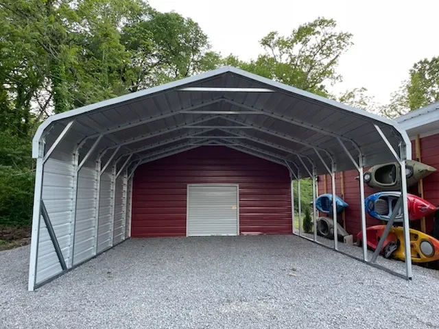 A large rounded frame carport with an enclosed shed section in the back with a garage door