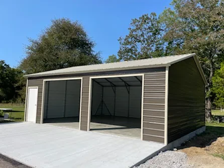 A brown metal garage with two garage door openings and a walk-in door in the front