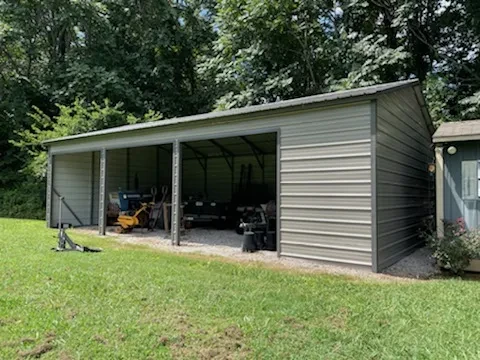 A large mostly enclosed metal building with multiple openings in the front for pulling vehicles and equipment through