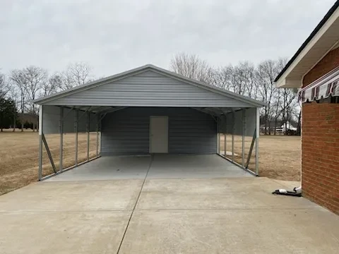 A gray squared frame carport with an enclosed shed area in the back