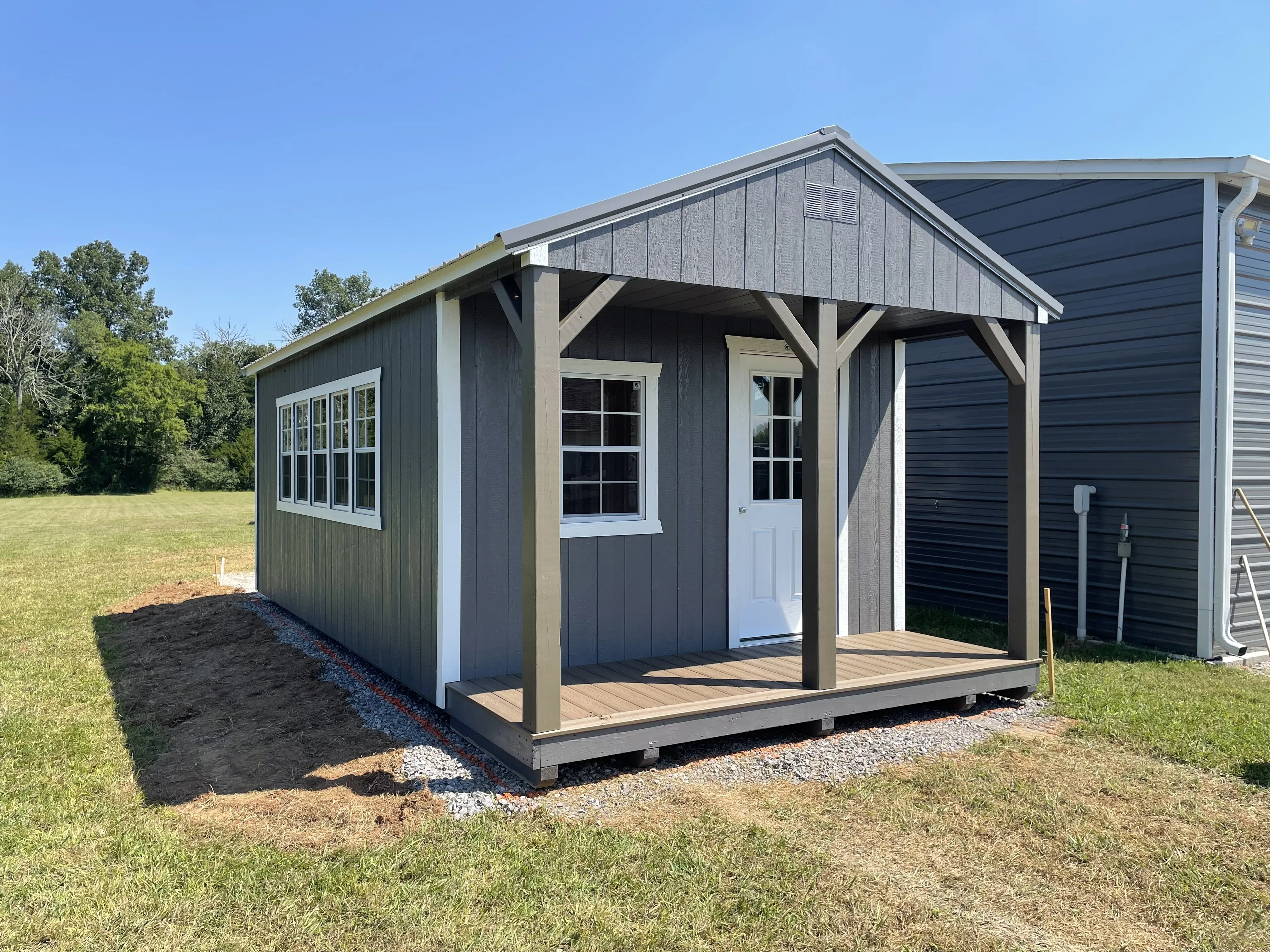 Gray Cabin with lots of windows down the side and a brown polywood porch
