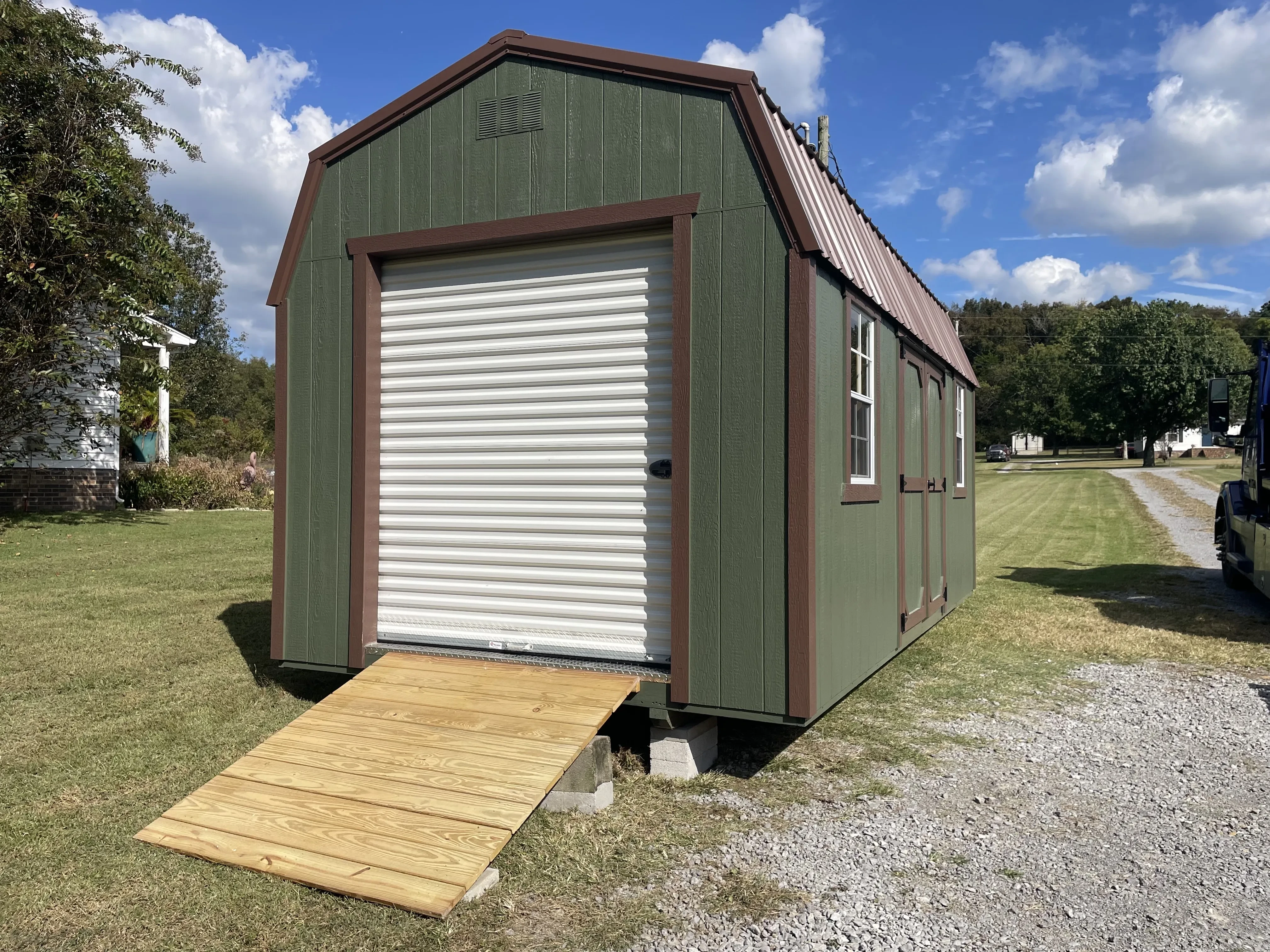 green lofted garage with brown trim and wood ramp