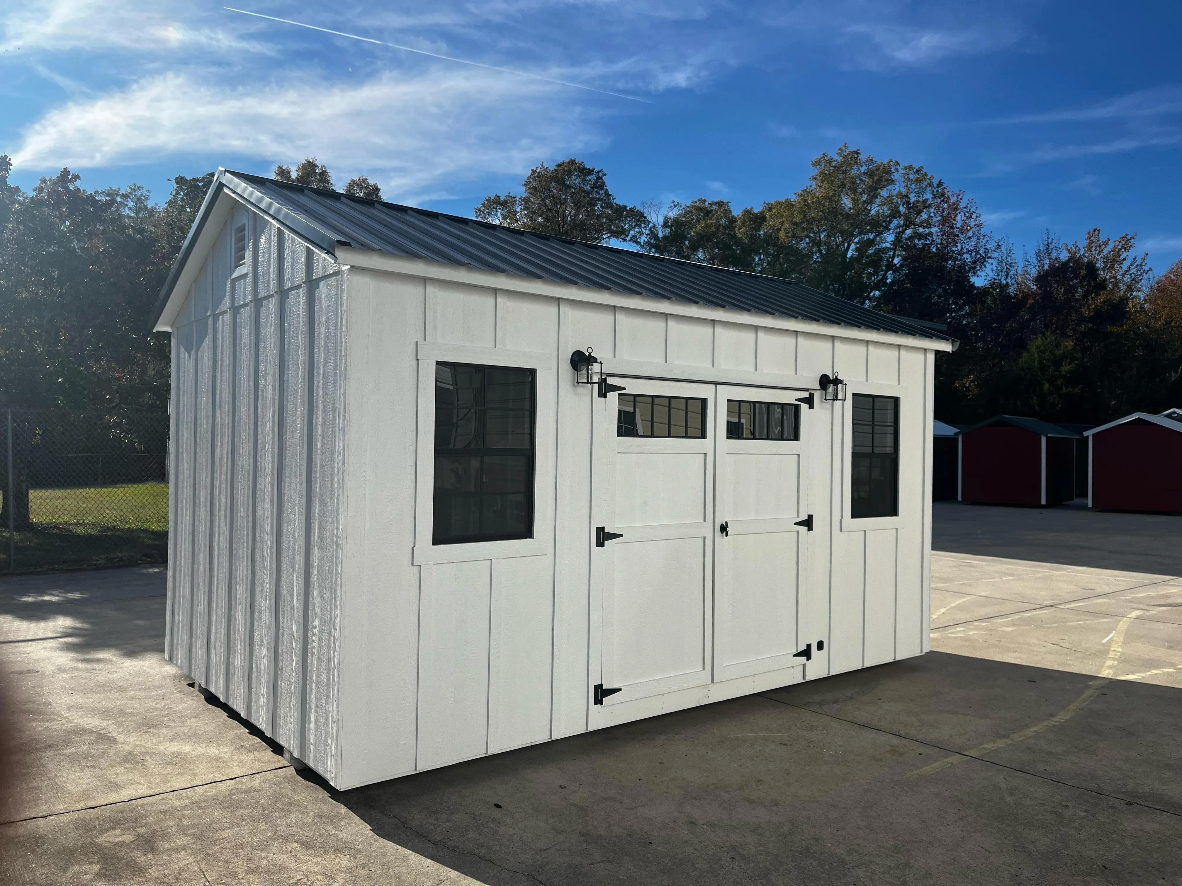 white board and batten garden shed with exterior lights and black windows
