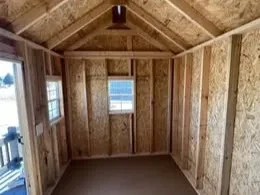 the inside of a wood playhouse looking at the left wall, it has a window and you can see the front door open