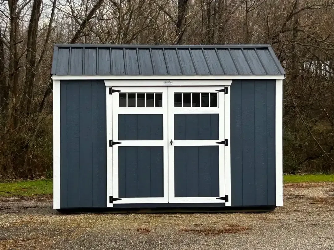a wood garden shed painted a royal blue color with white trim and a black roof. It has double doors