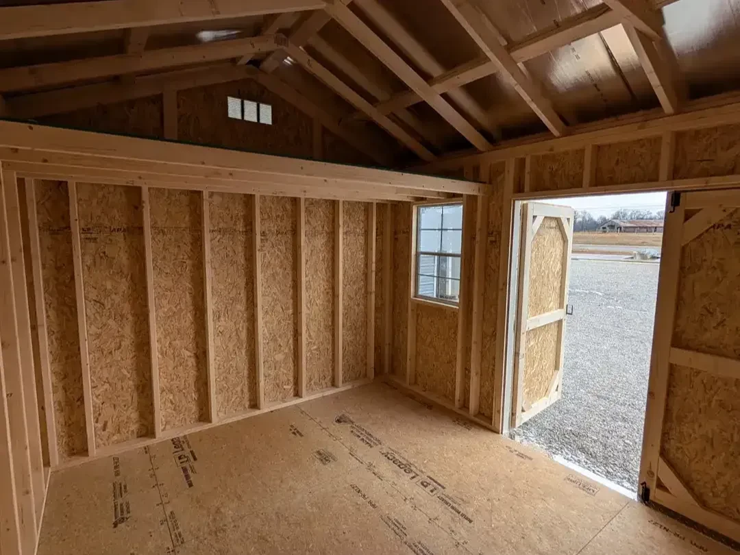 the inside of a wood garden shed looking towards the left wall. It has a 4' loft and a vent above it