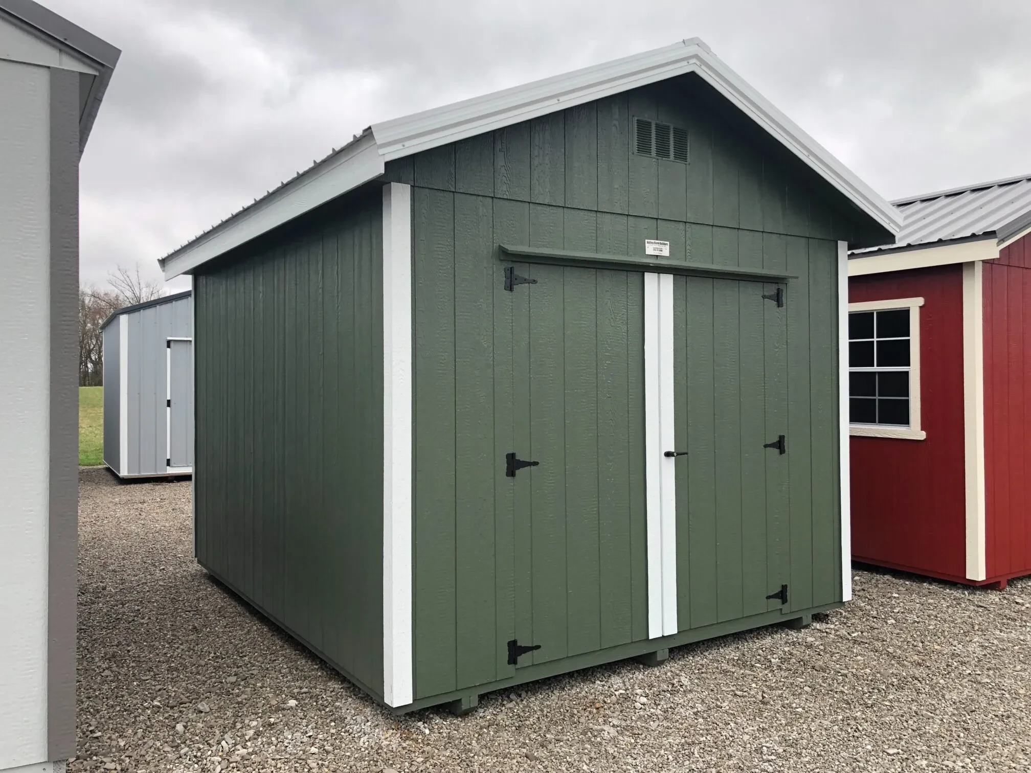 A green shed with white trim between other sheds