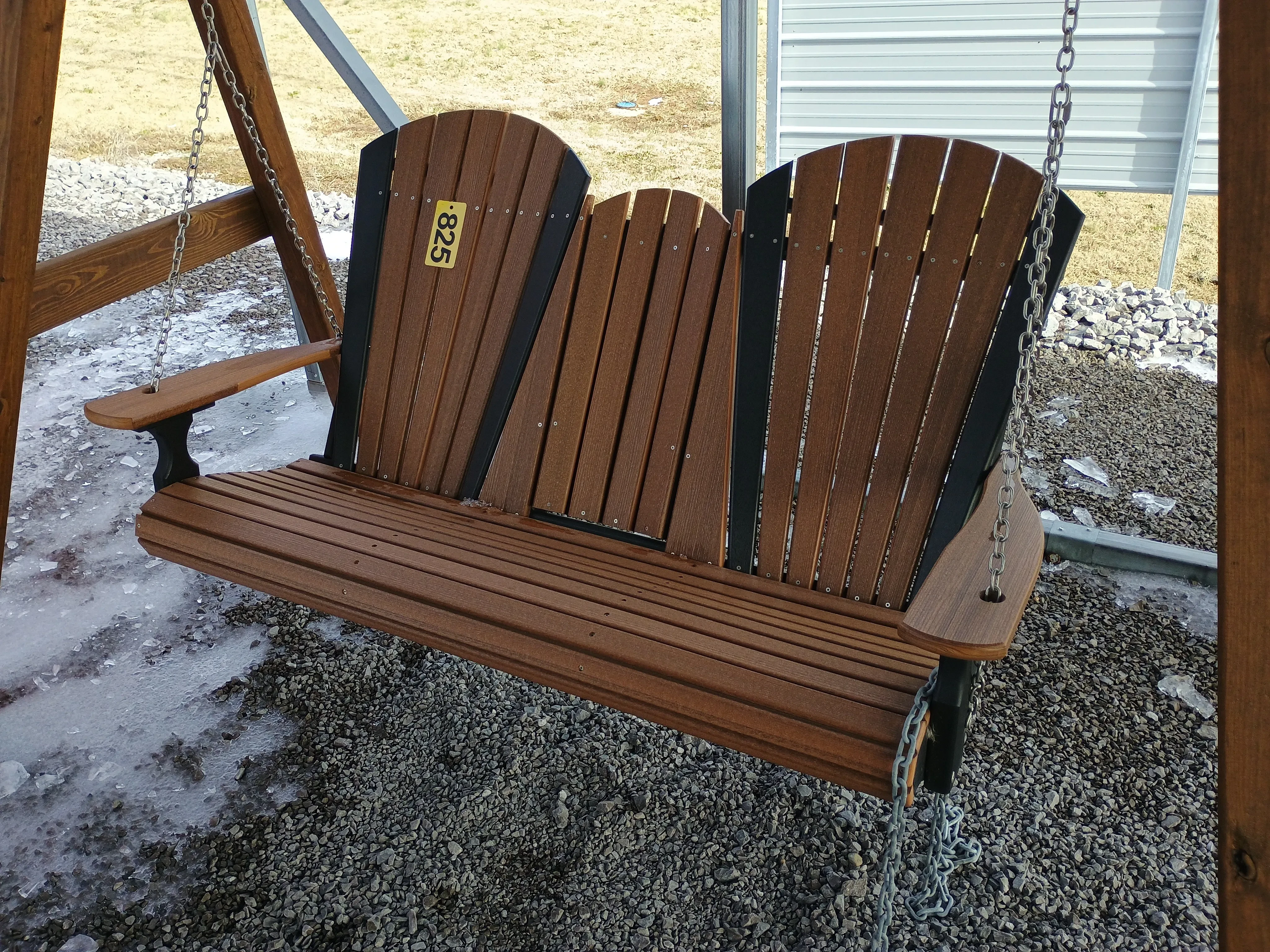 a bench swing attached to a swing cover. there is ice on the ground in the background