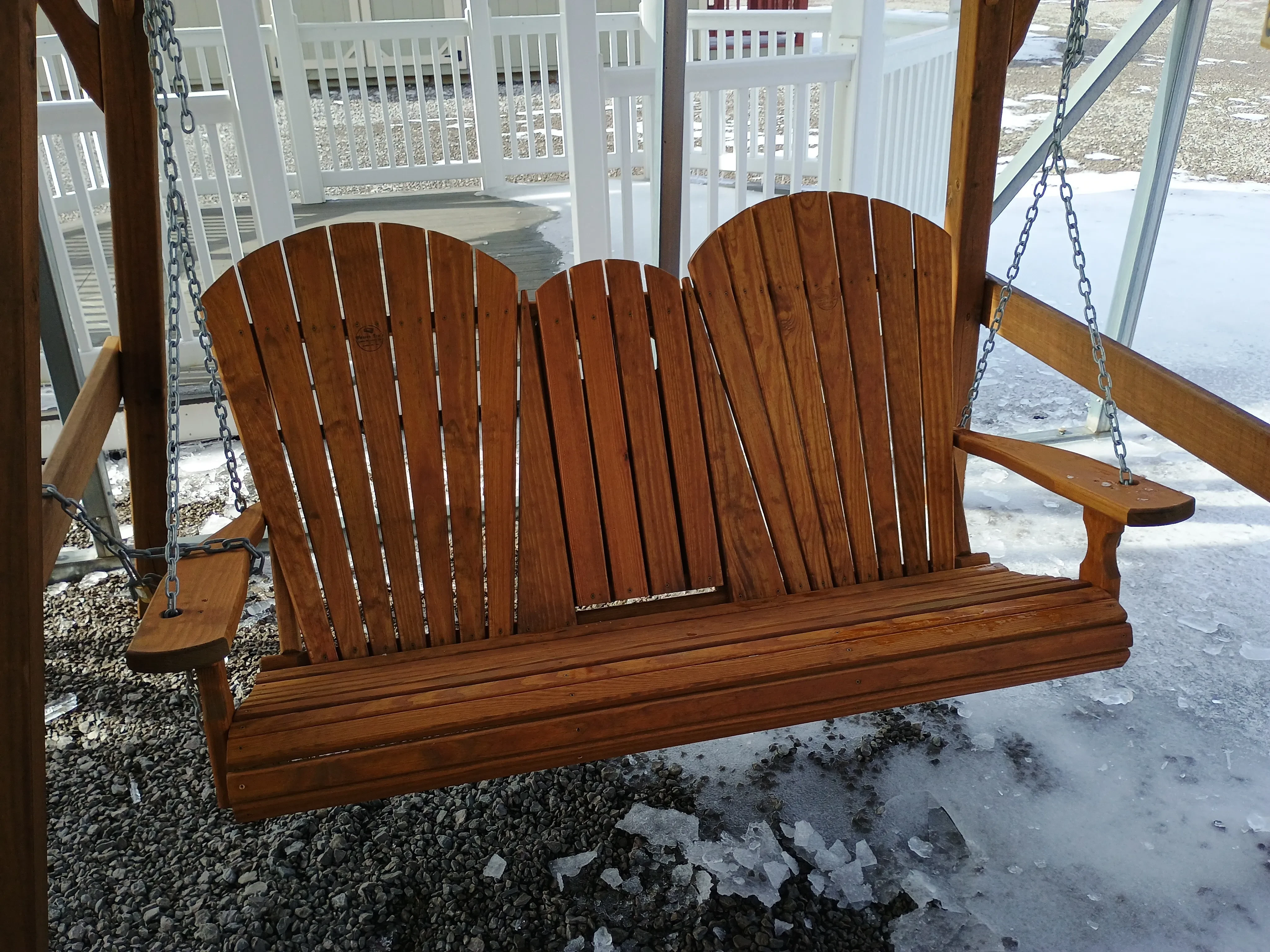 a stained wood bench swing with the center console in the upright position
