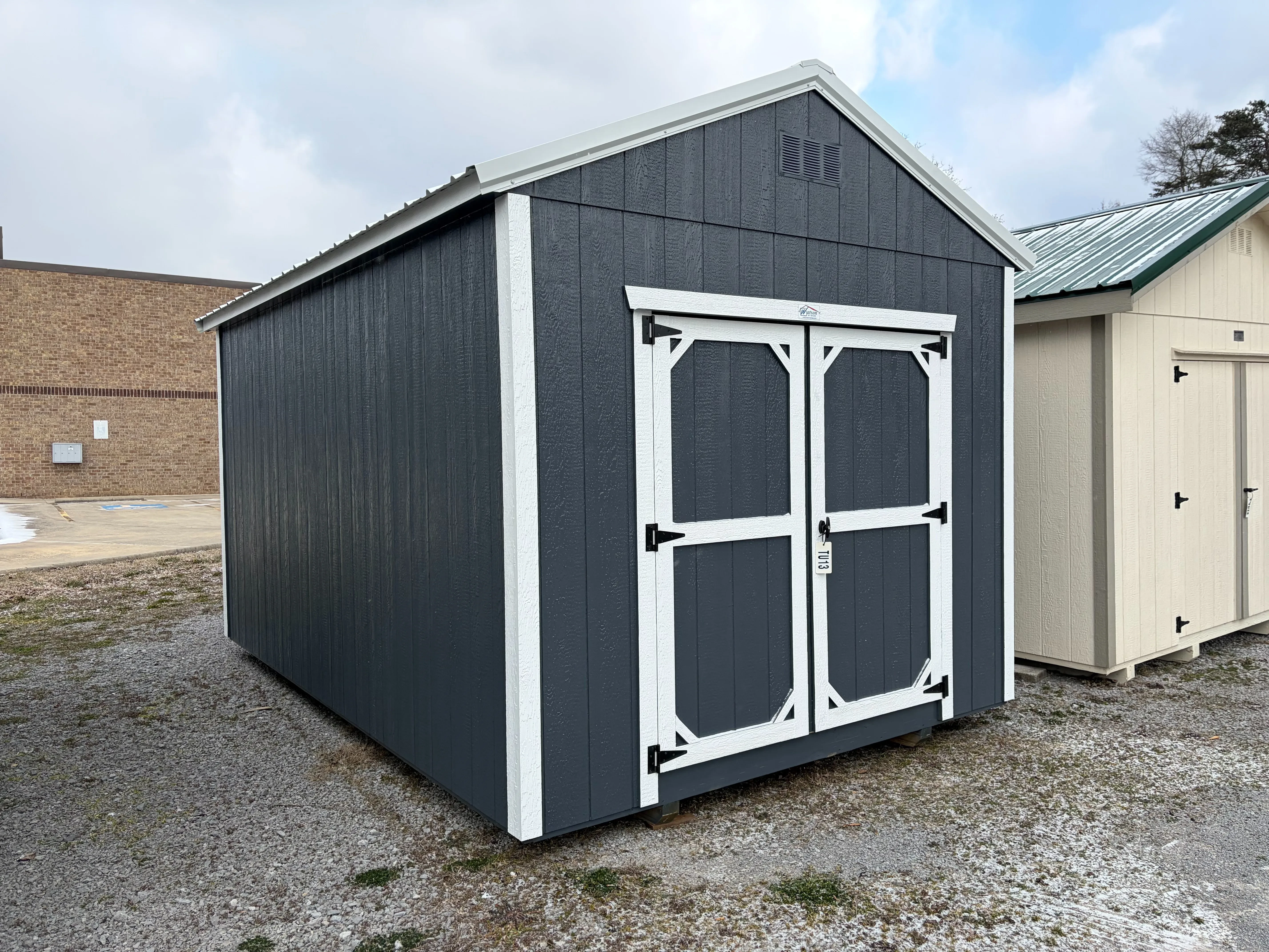the a slate gray utility shed with double doors and a roof overhang, it also has white roof trim and white wall trim