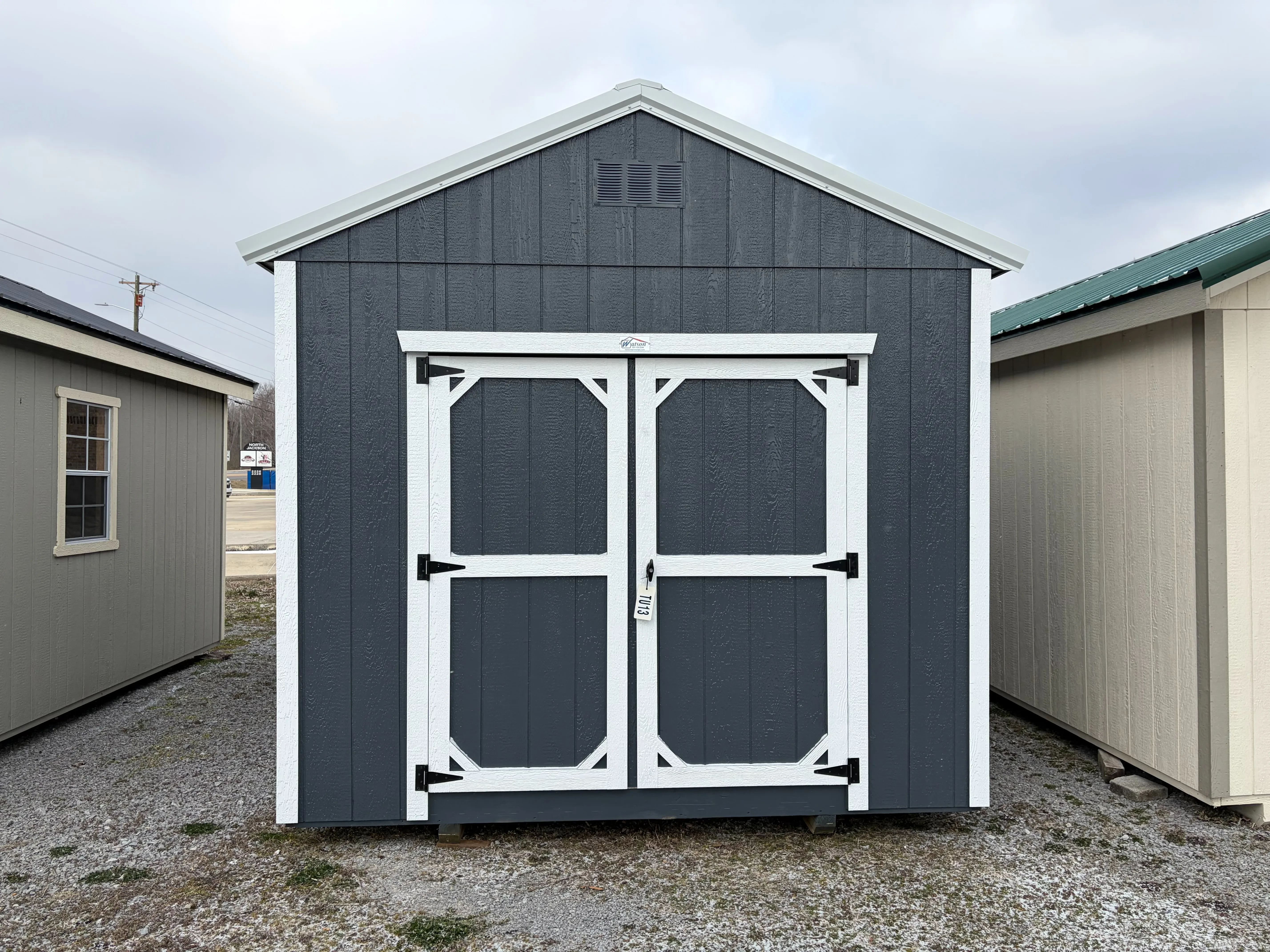 the a slate gray utility shed with double doors and a roof overhang, it also has white roof trim and white wall trim