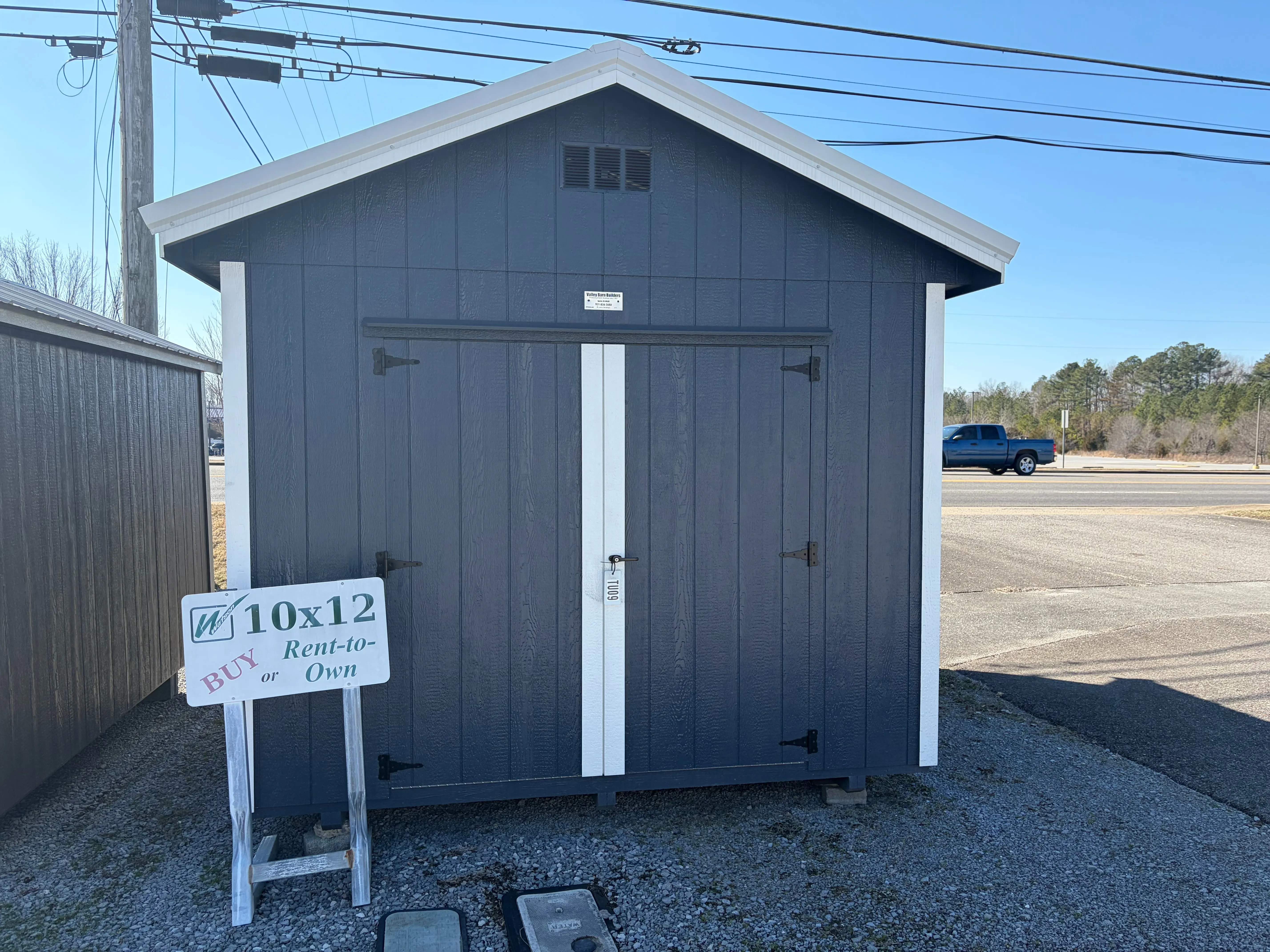 he a blue utility shed with double doors and a roof overhang, it also has white roof trim and white wall trim
