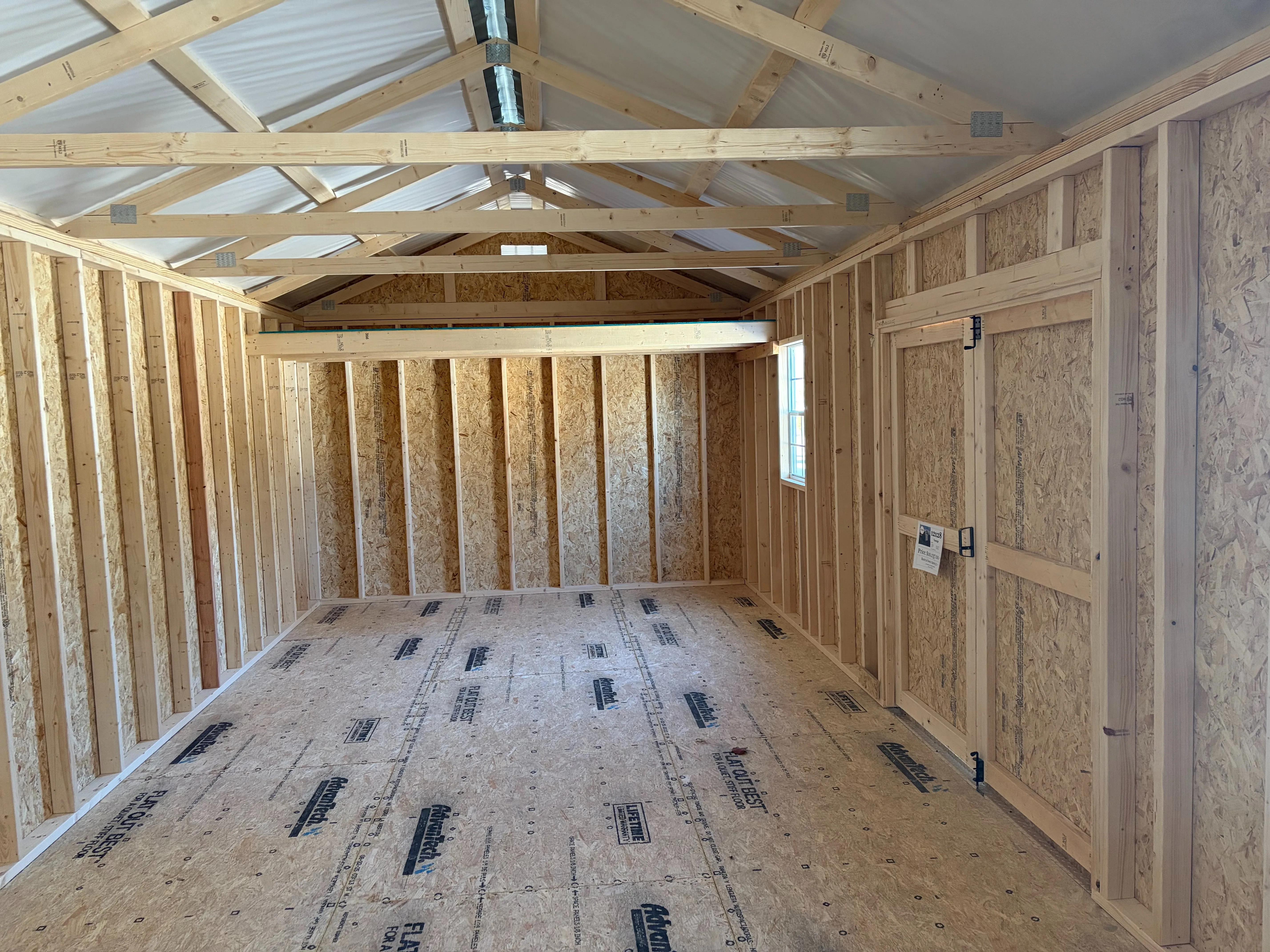 the inside a large garage shed with multiple windows, a loft, and double doors that are closed