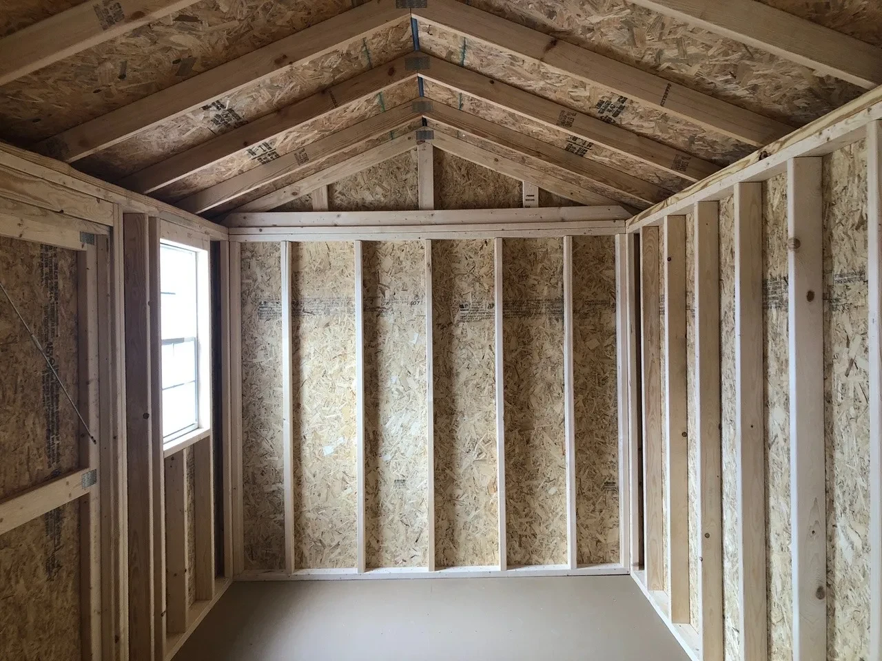inside wood shed showing the floor and framing and window