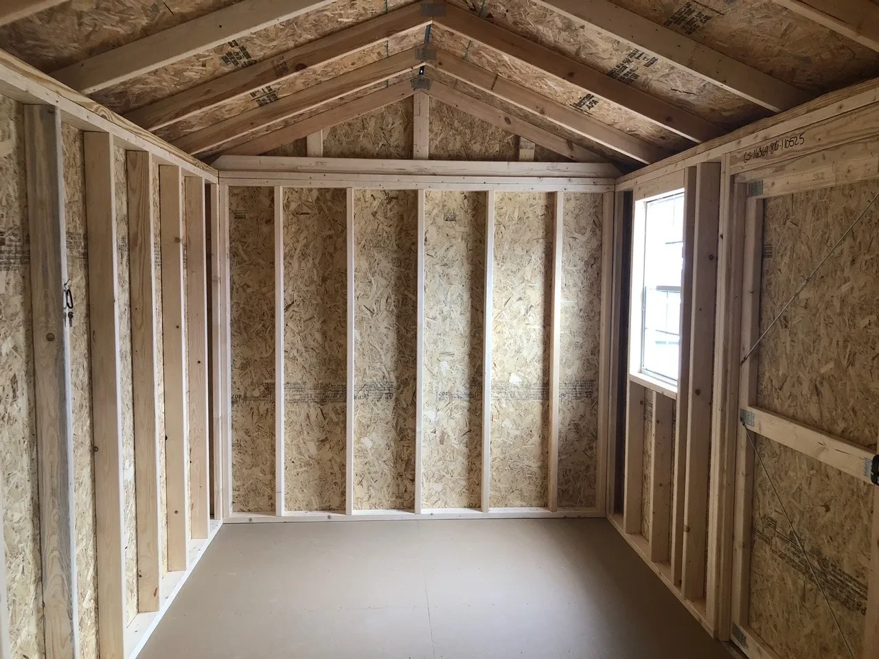 inside wood shed showing the floor and framing and window