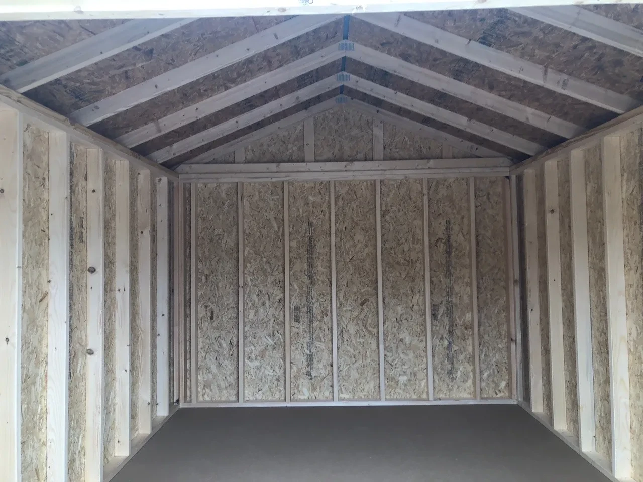 inside wood shed showing the floor and framing