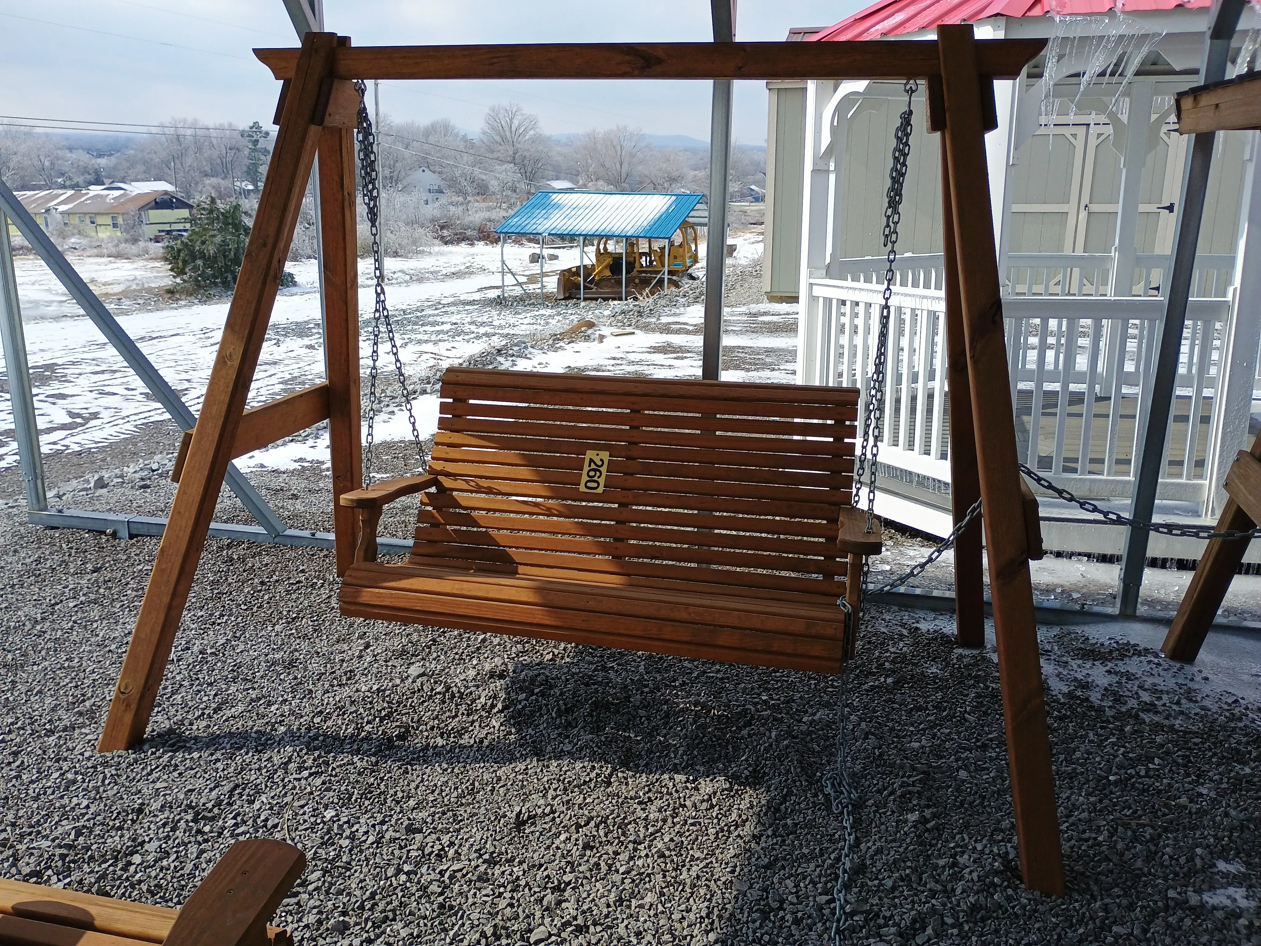 a wood bench with planks running horizontally. It is attached to two a-frames by a chain