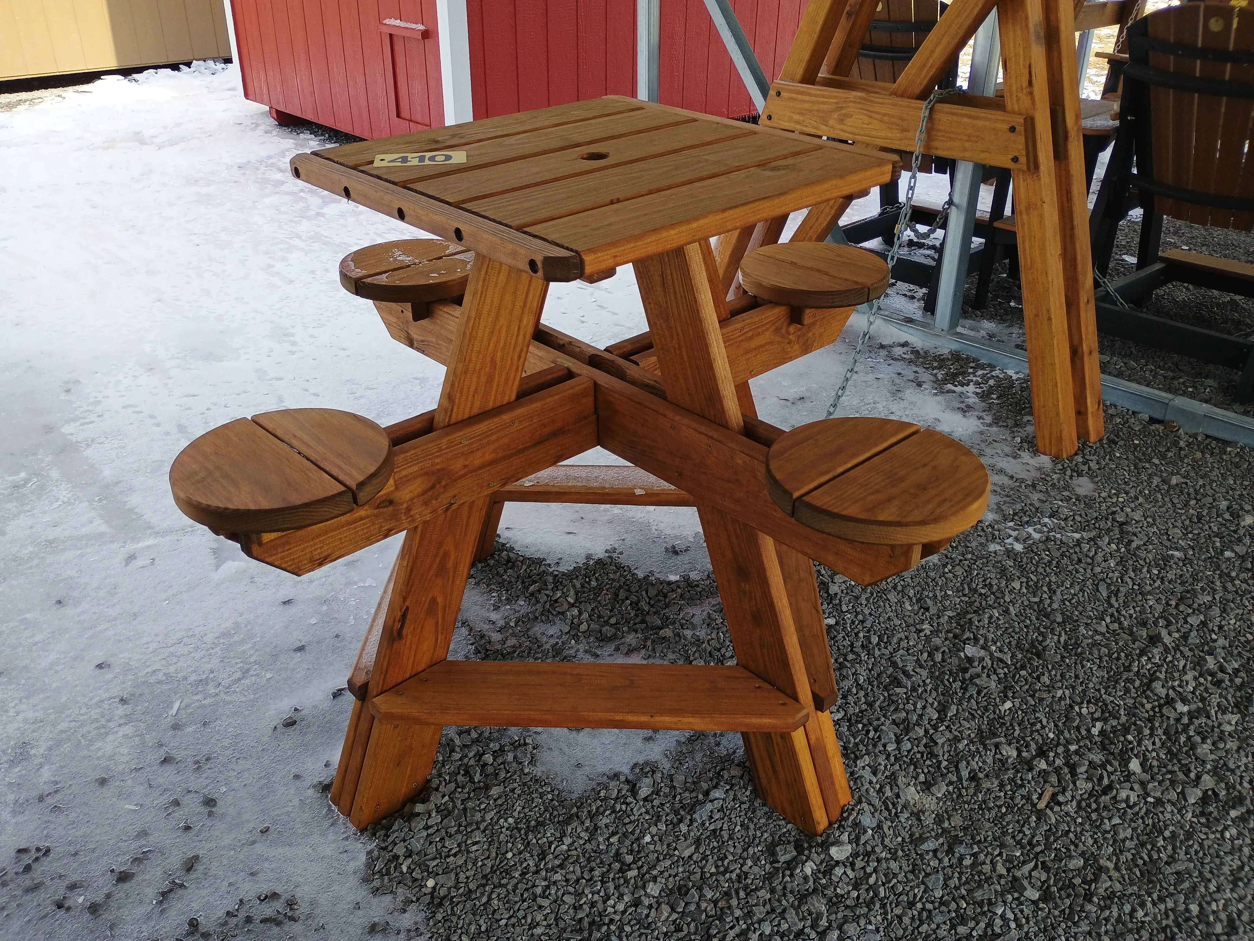 a table with four circular seats, it has a square shaped table top with five horizontal planks