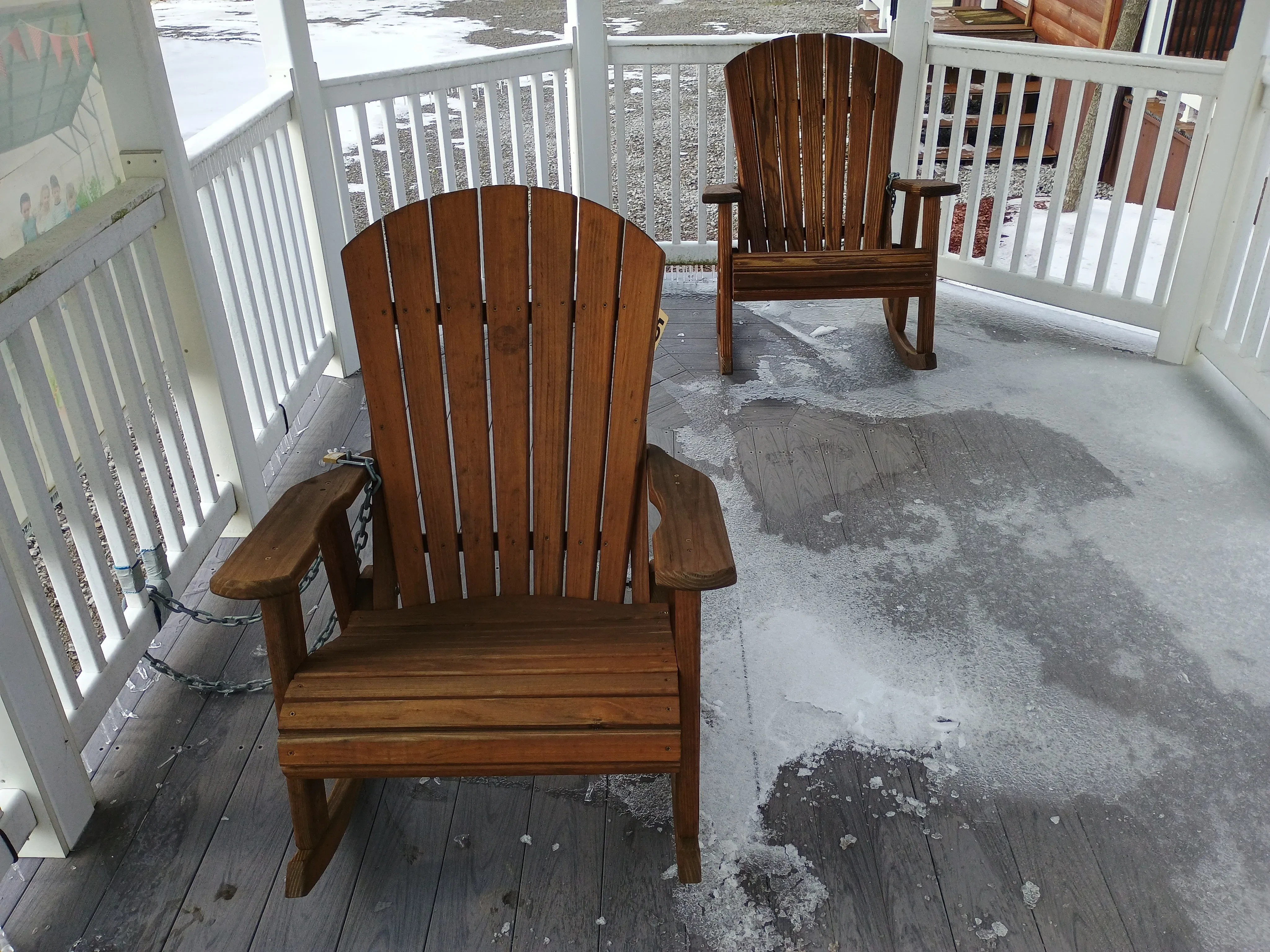 inside a gazebo that has two wood stained rocking chairs. There is ice on the ground nearby