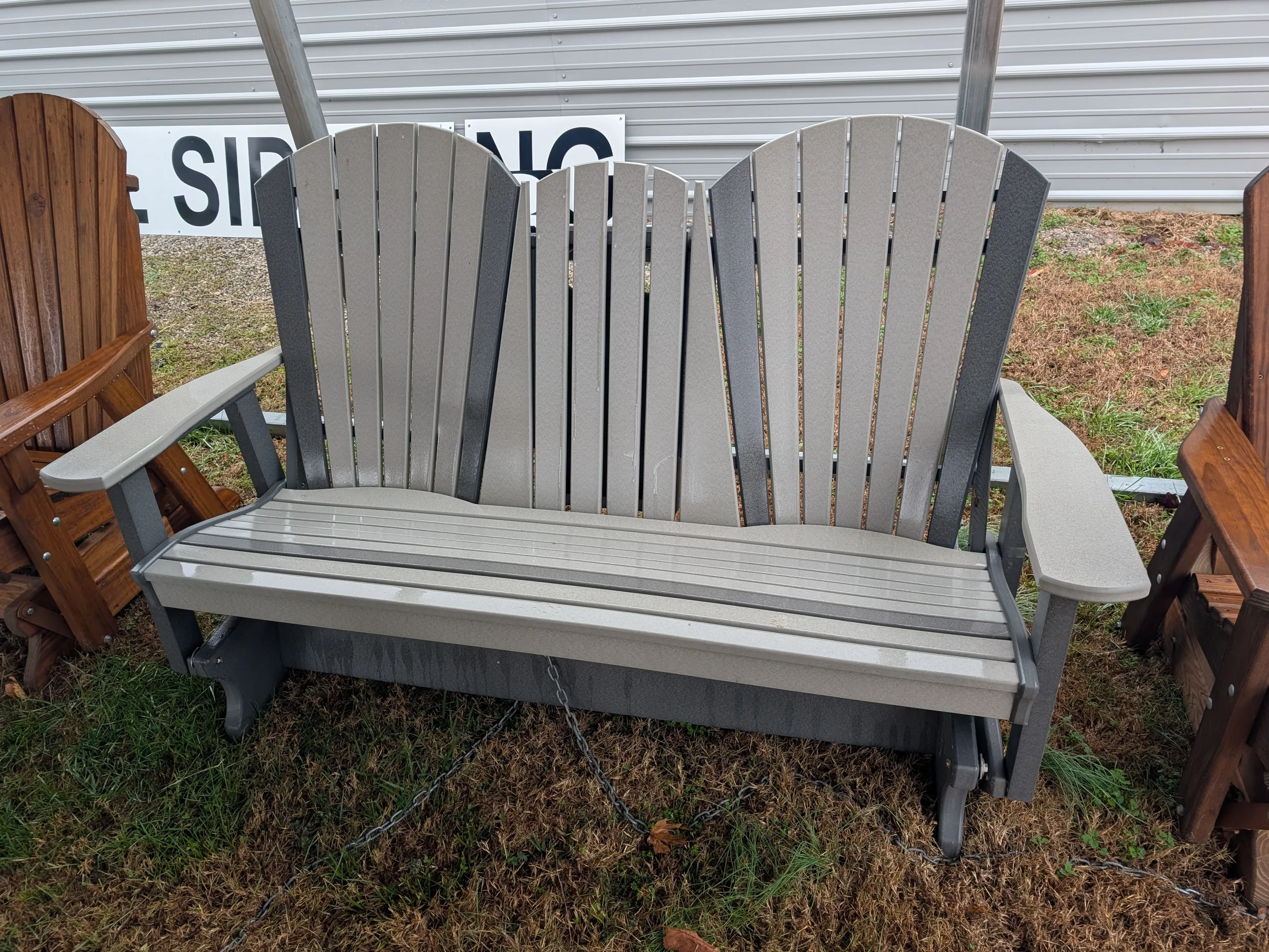 a light gray bench sitting in the grass. It has dark gray accents and a center console in the up position