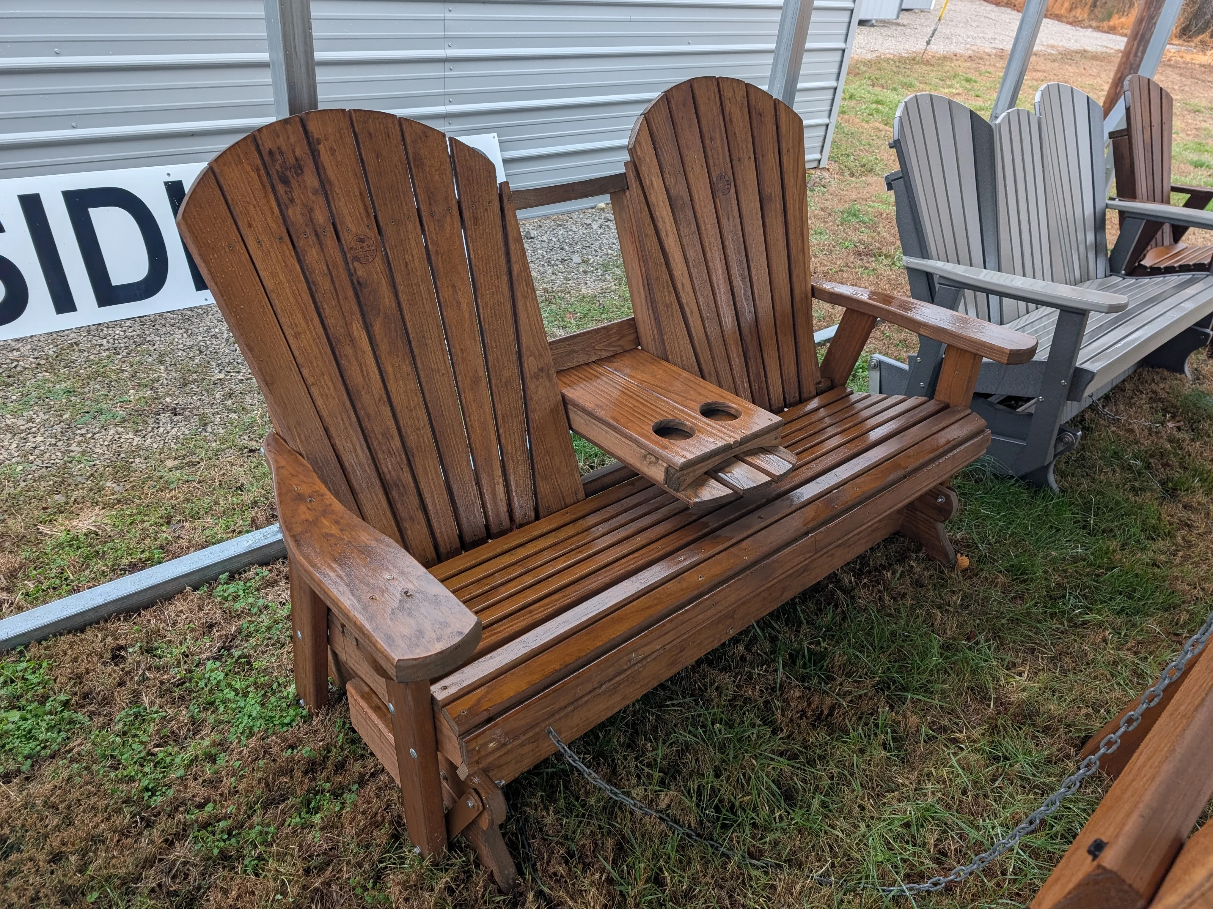 a wood stained bench with arm rests and a center console with cupholders in the down position