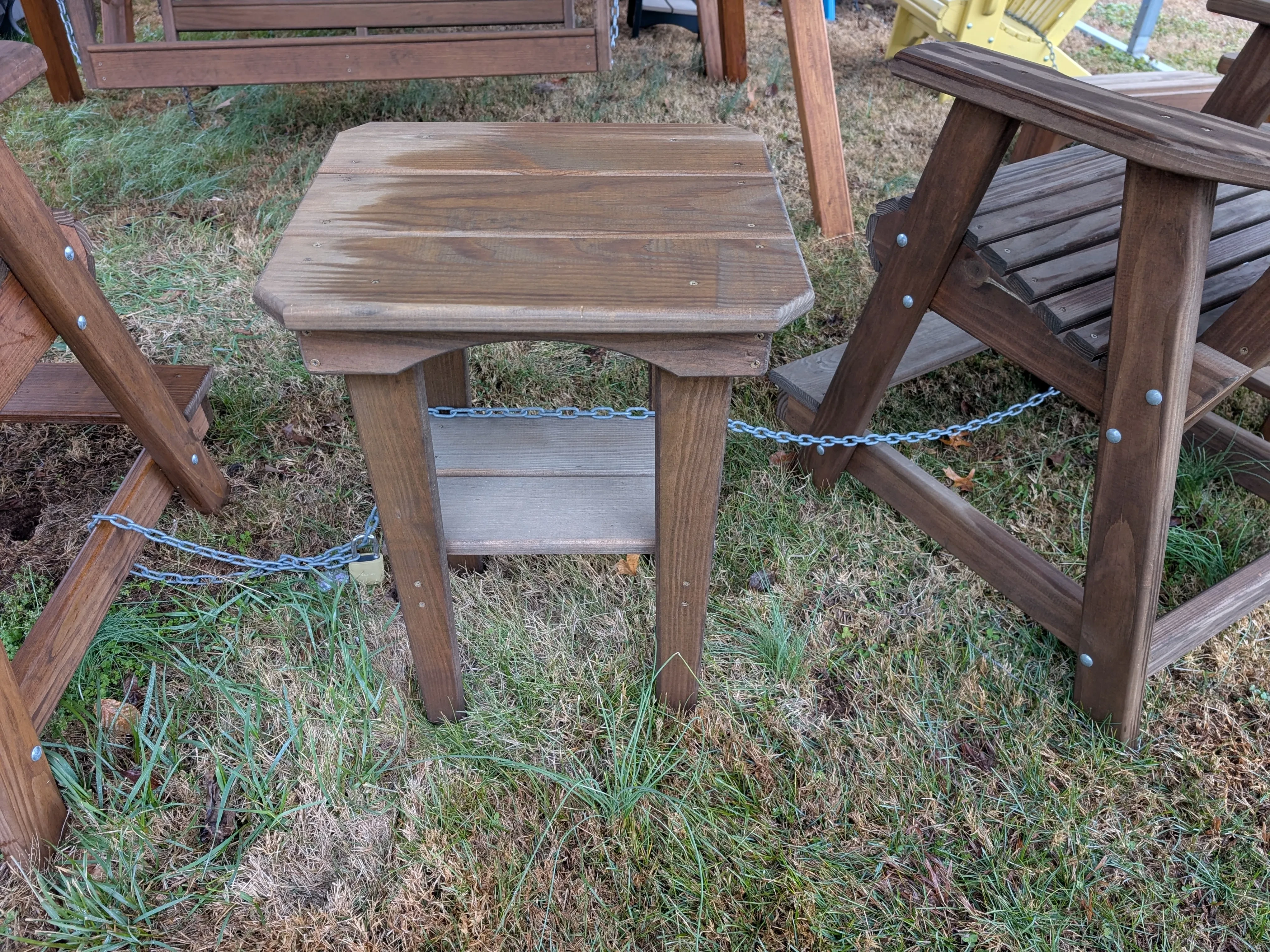 a wood stained and sealed table. It is in the grass and chained up to other furniture