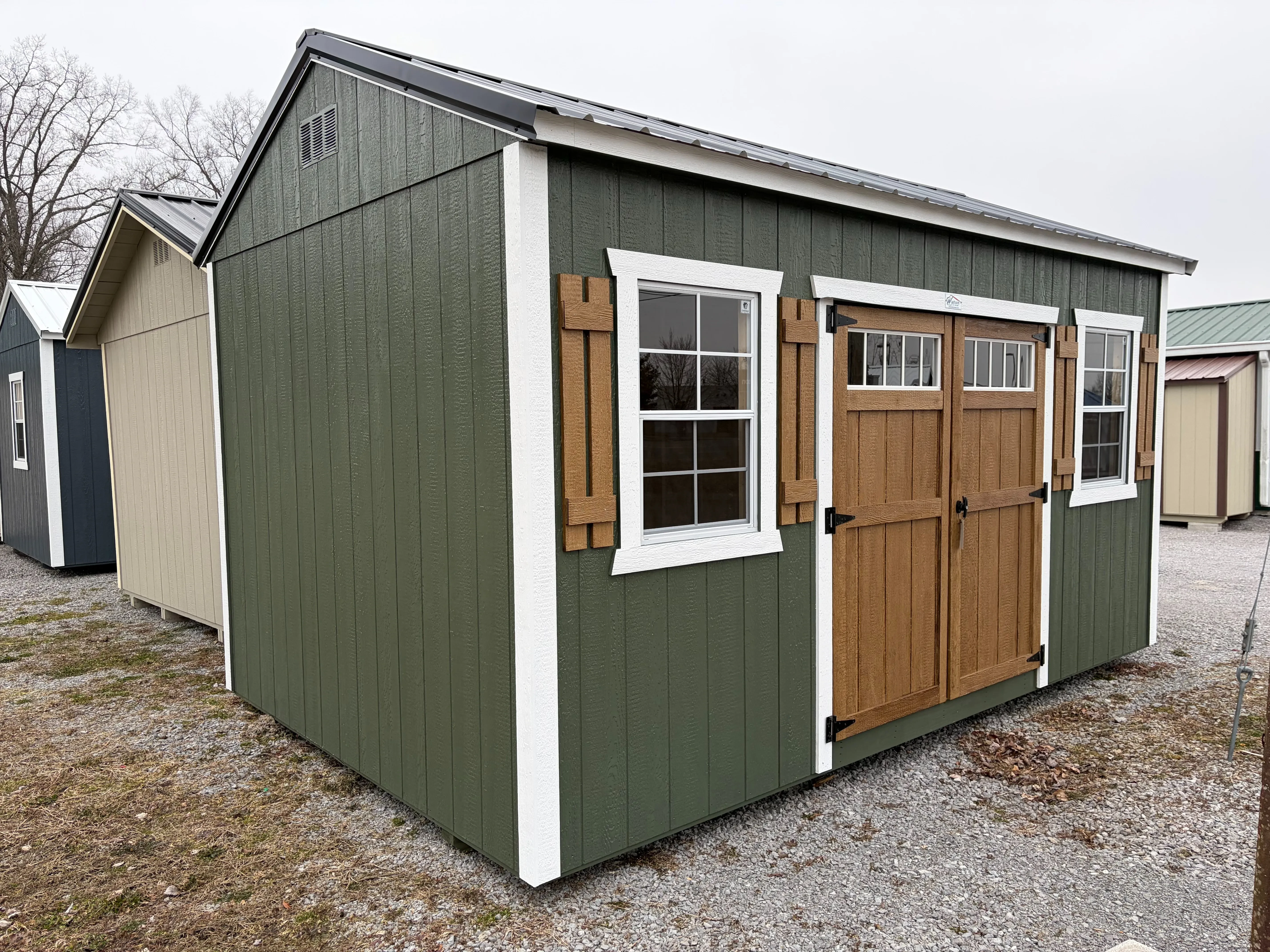 outside of a 10x16 garden shed with stained double doors and 2 windows with stained shutters