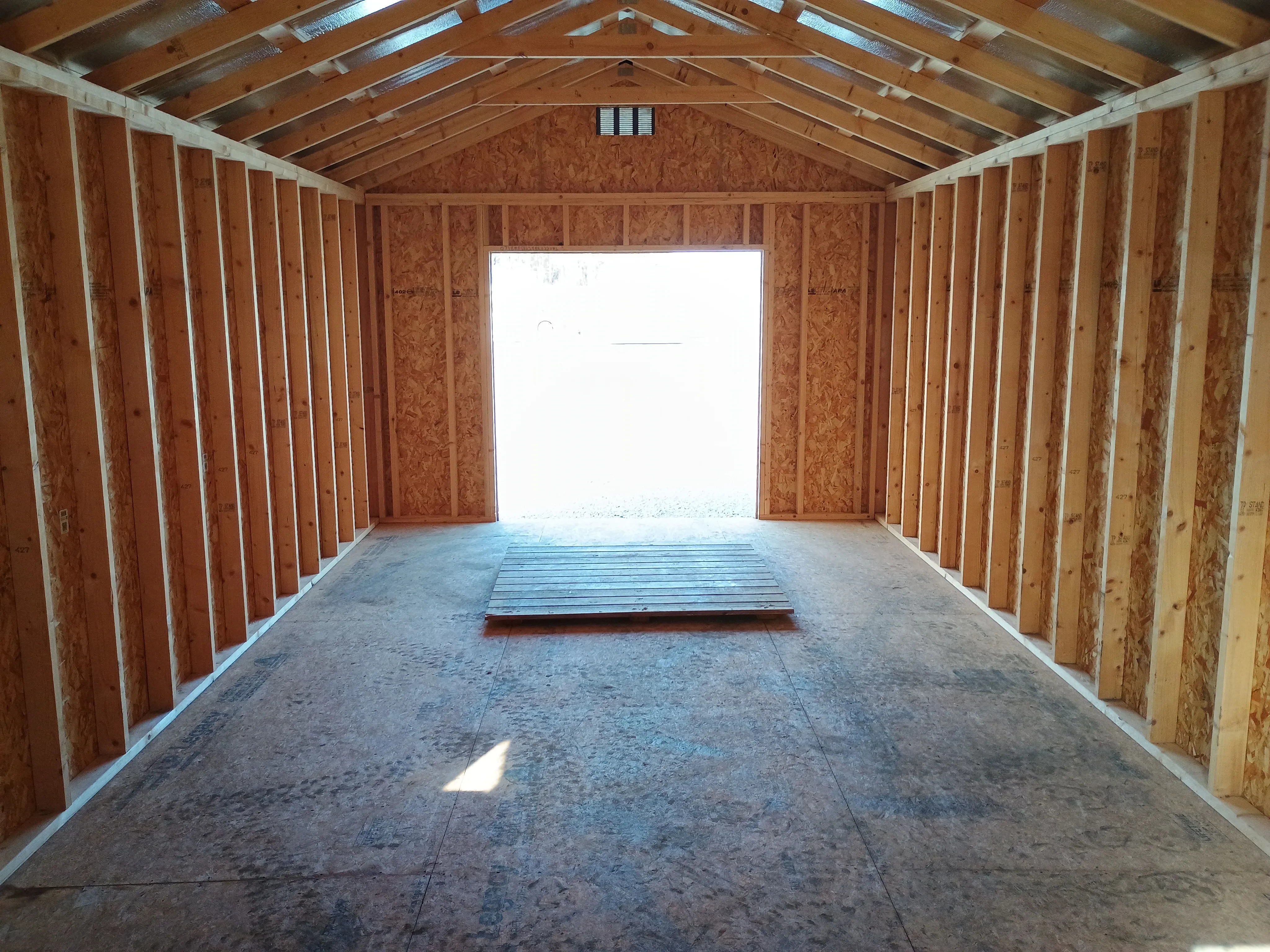 interior of 12x28 premium wood utility REPO shed, looking back out the the open front doors, also showing included wood ramp