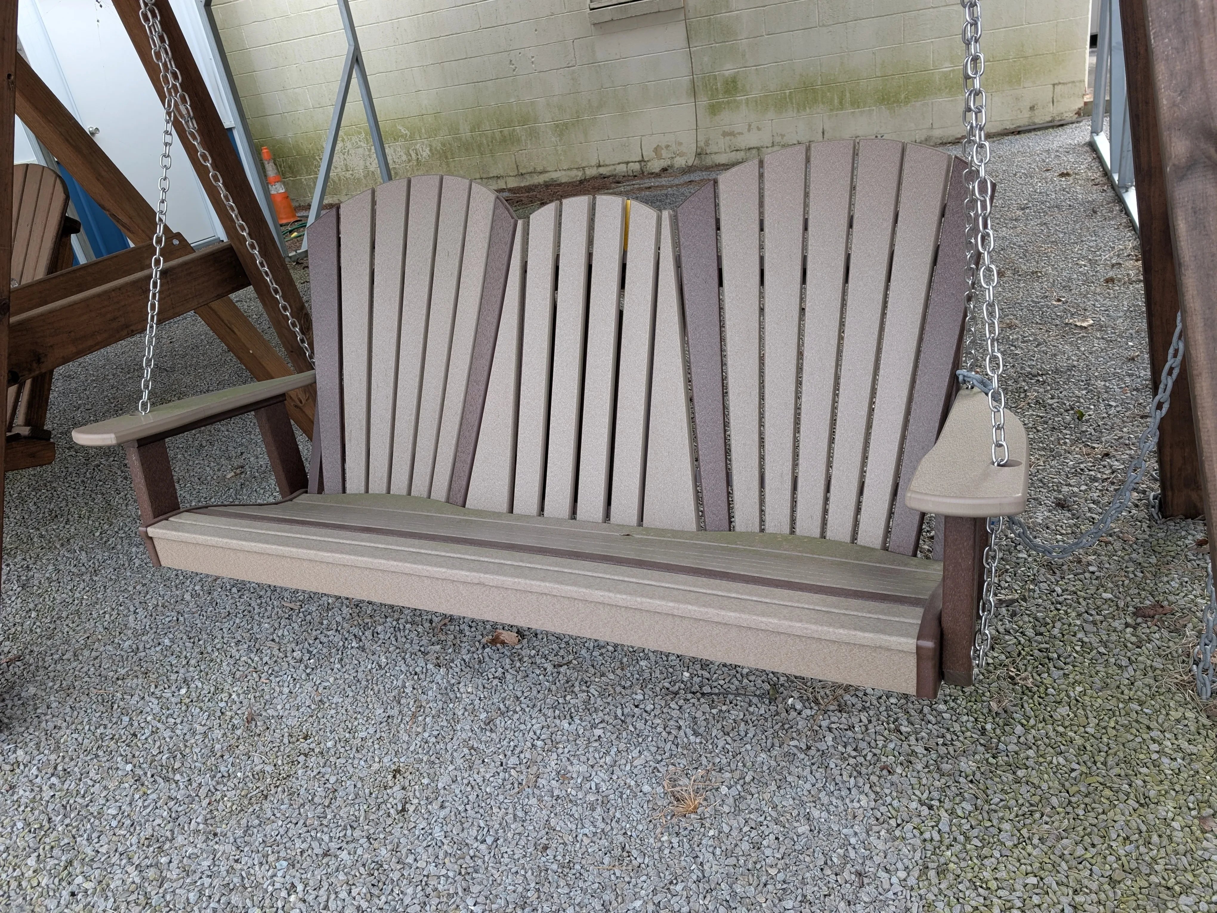 a light gray bench swing held up by chains. It is above gravel and has dark gray accents.