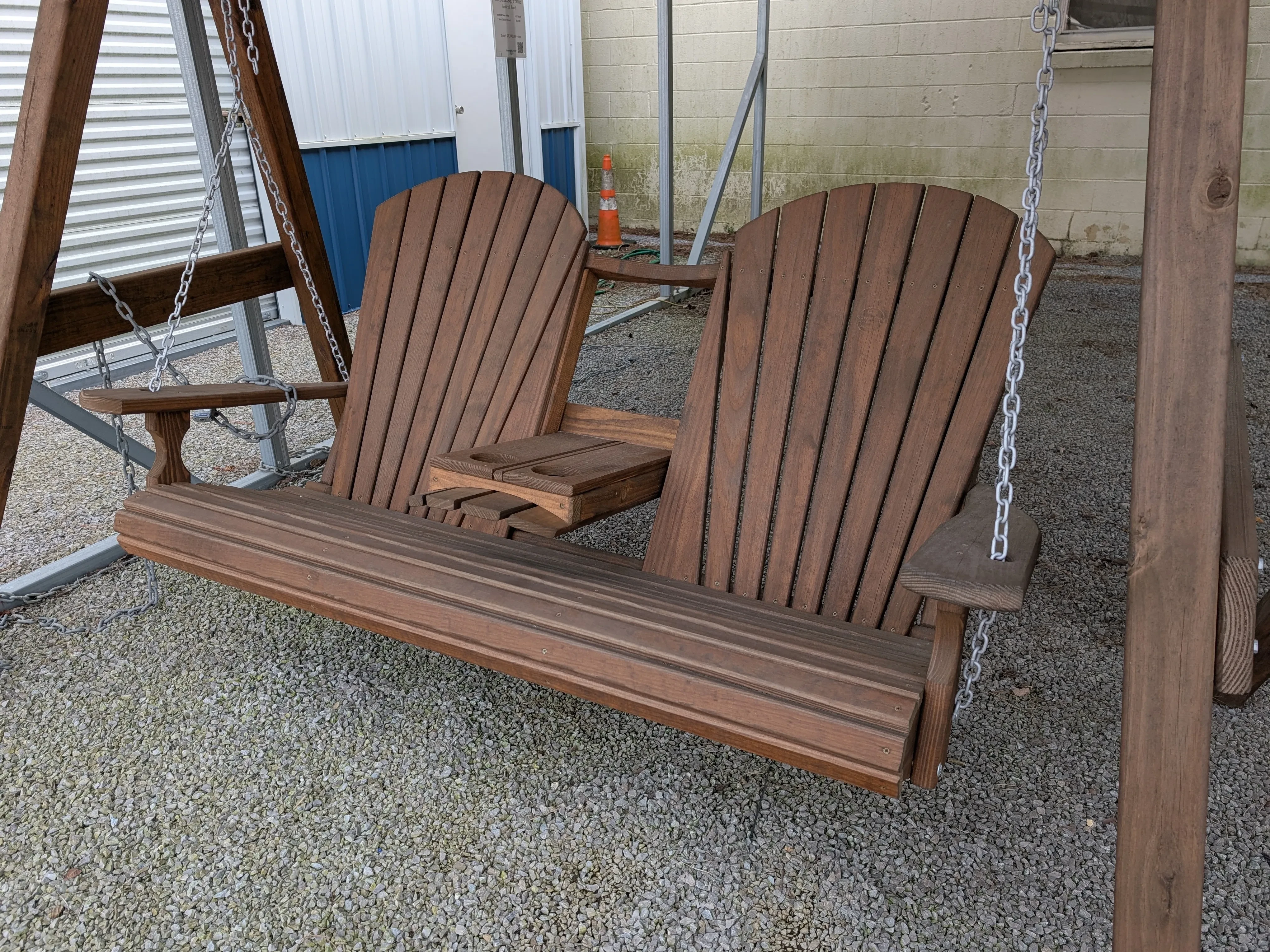 a wood swing with a center console that has two cupholders. It is held up by chains attached to an a-frame.